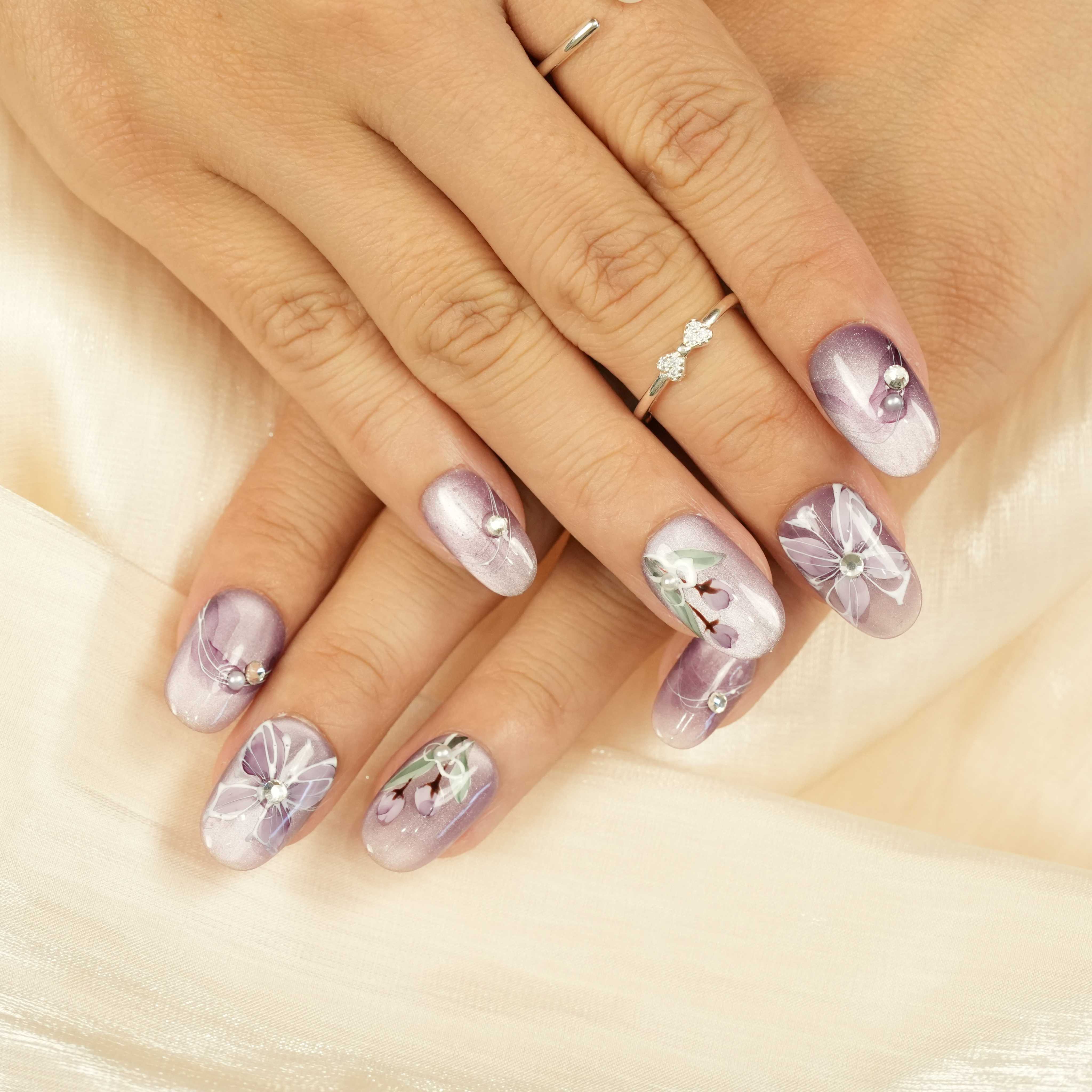 Purple floral press on nails featuring hand-painted white flowers, rhinestone accents, and soft ombré lavender base. Handmade glue-on nails Australia