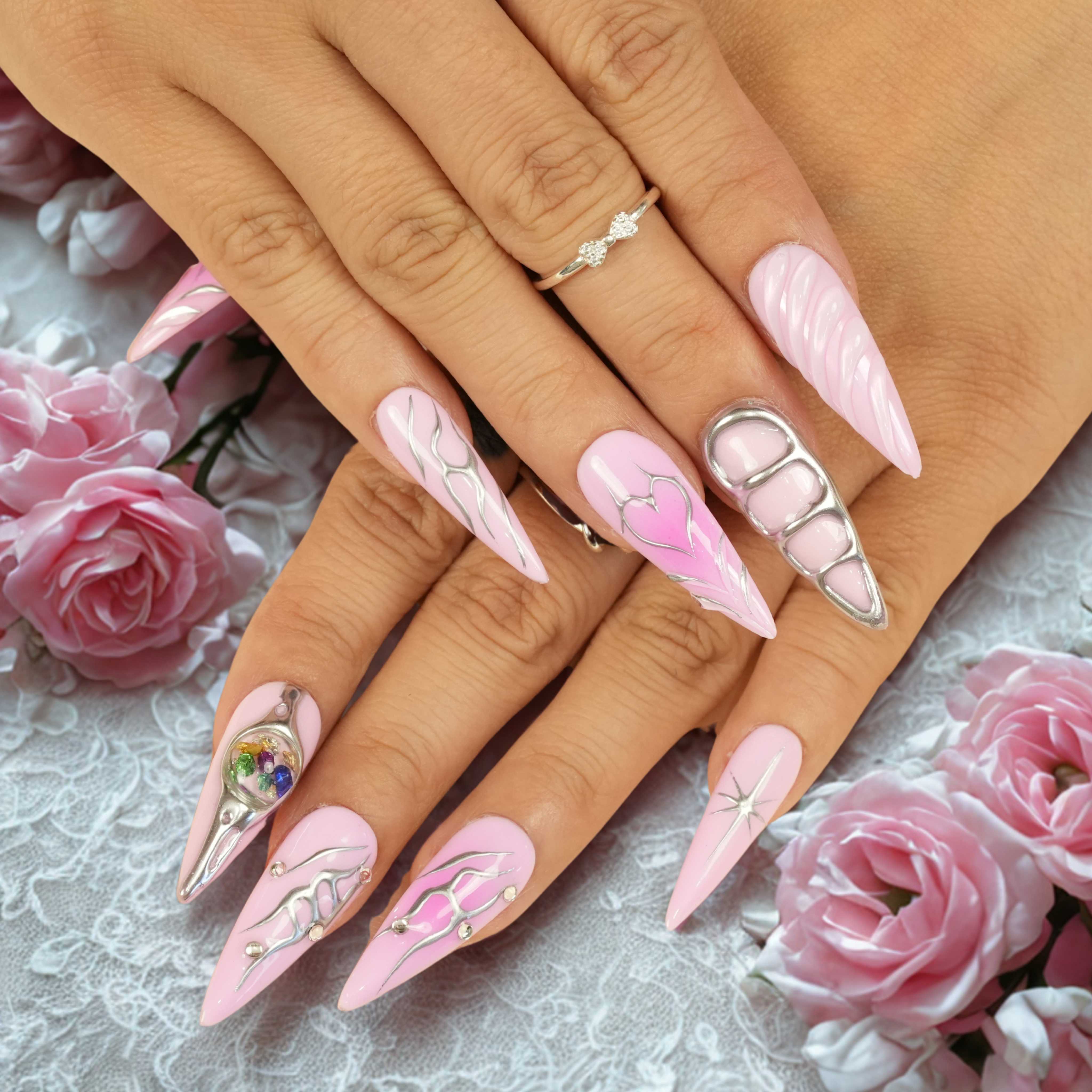 Hand with pink press on nails, soft pink base, chrome detailing, 3D grid nail art, and silver cosmic accents