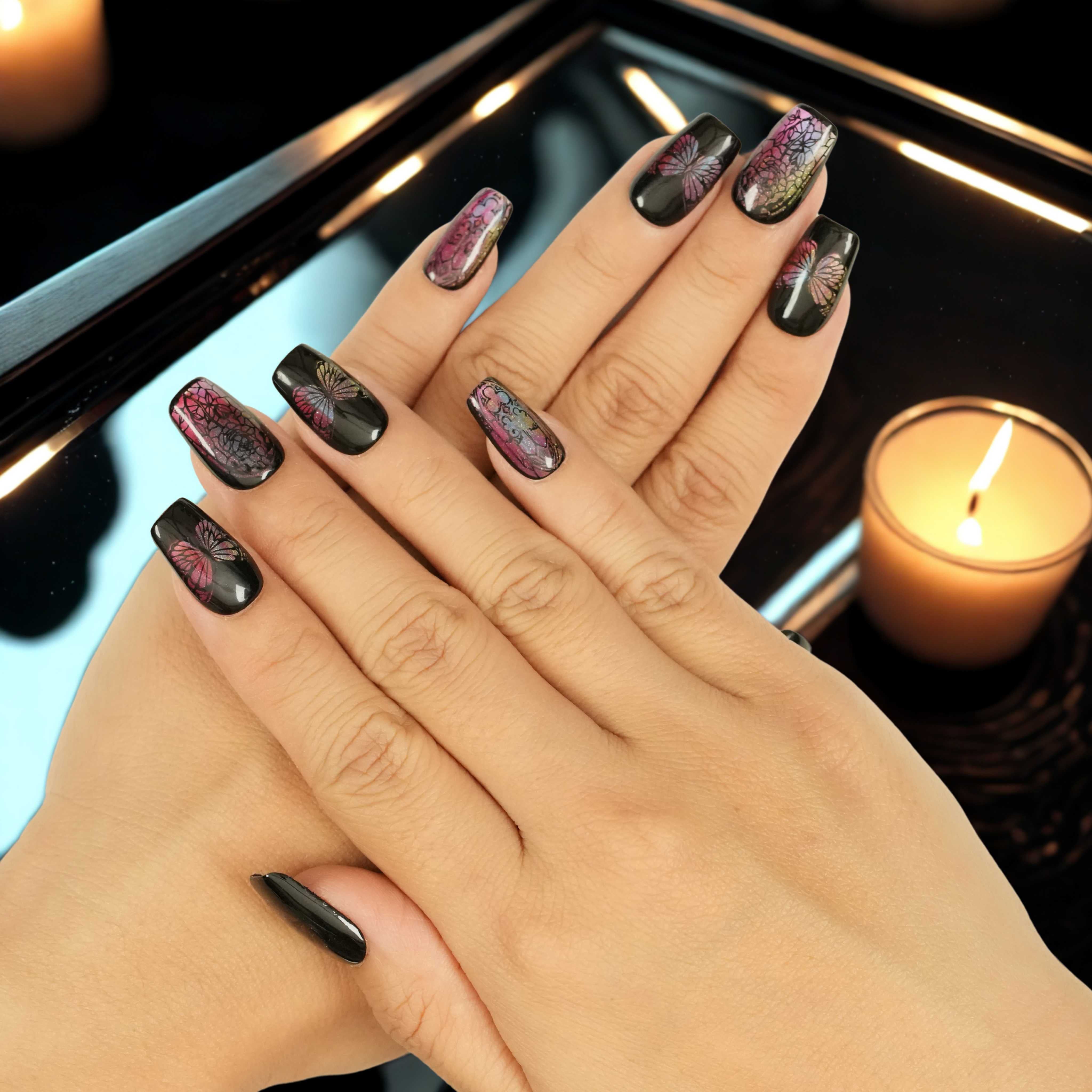 Handmade artificial nails featuring stained glass butterfly wings and gothic vibes, shown on both hands with candle background. Glue on nails Australia