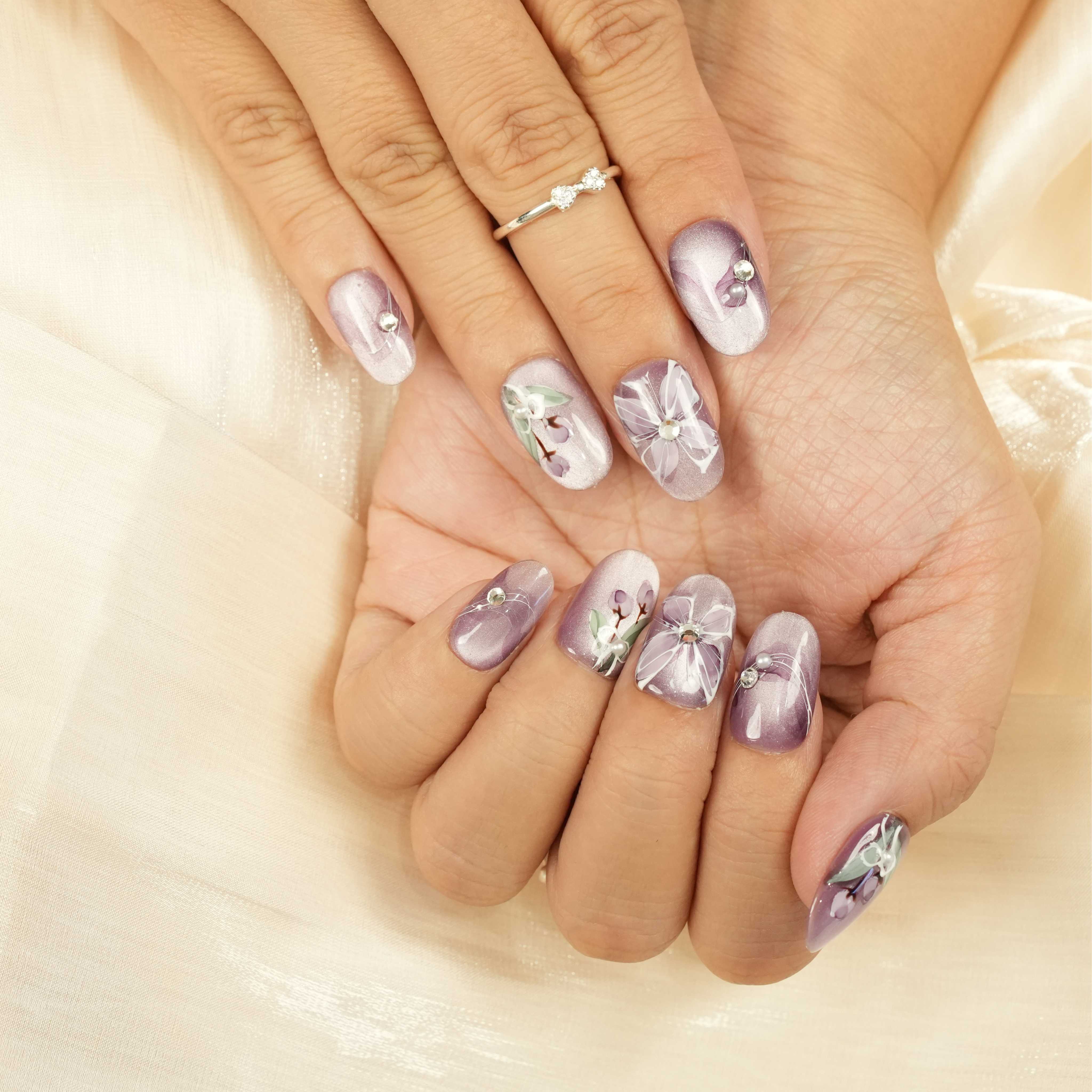 Handcrafted lilac press on nails with delicate floral artwork, 3D rhinestones, and pastel lavender base. Short glue on nails Australia
