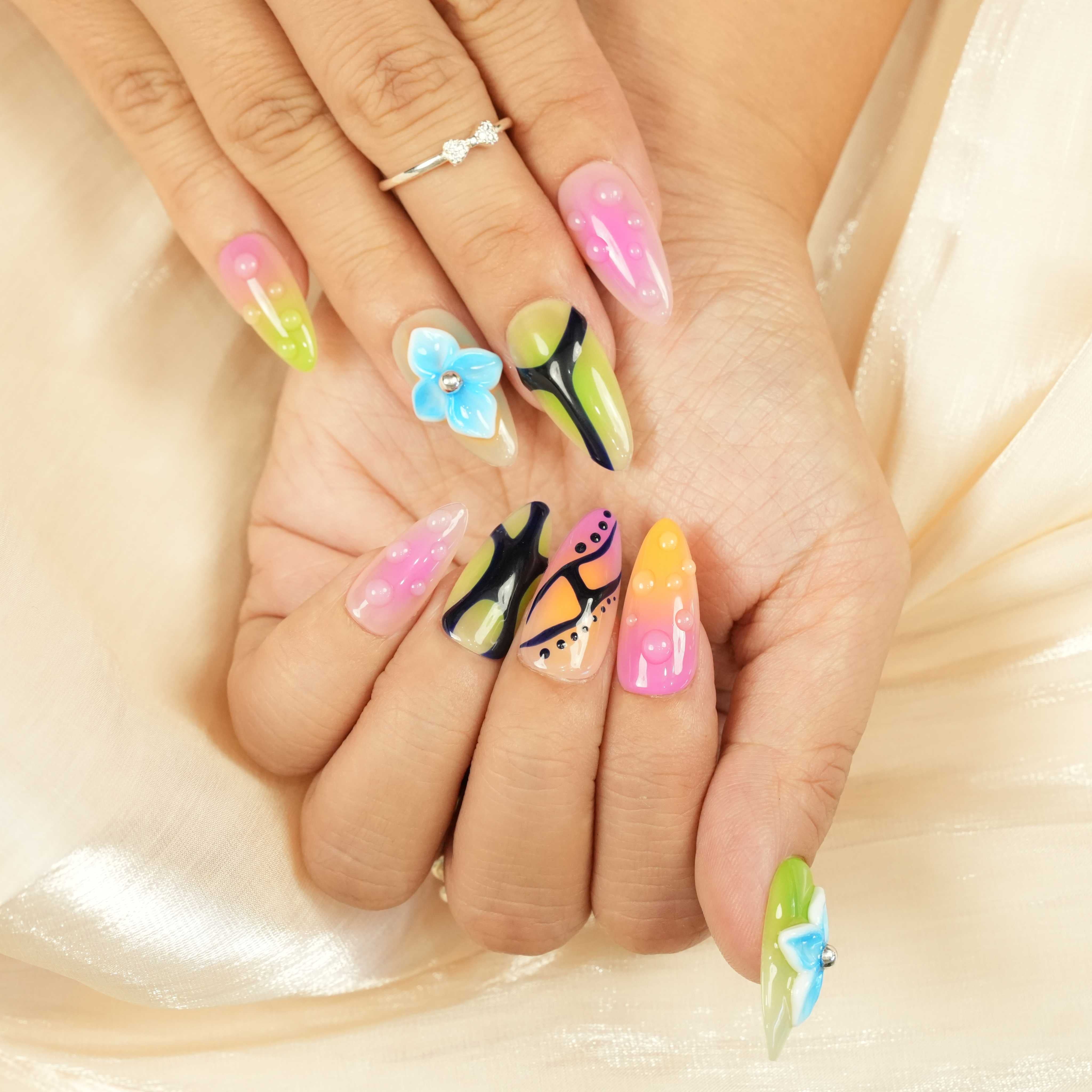 vibrant glue on nails with retro pink, orange, and green patterns and glossy beads