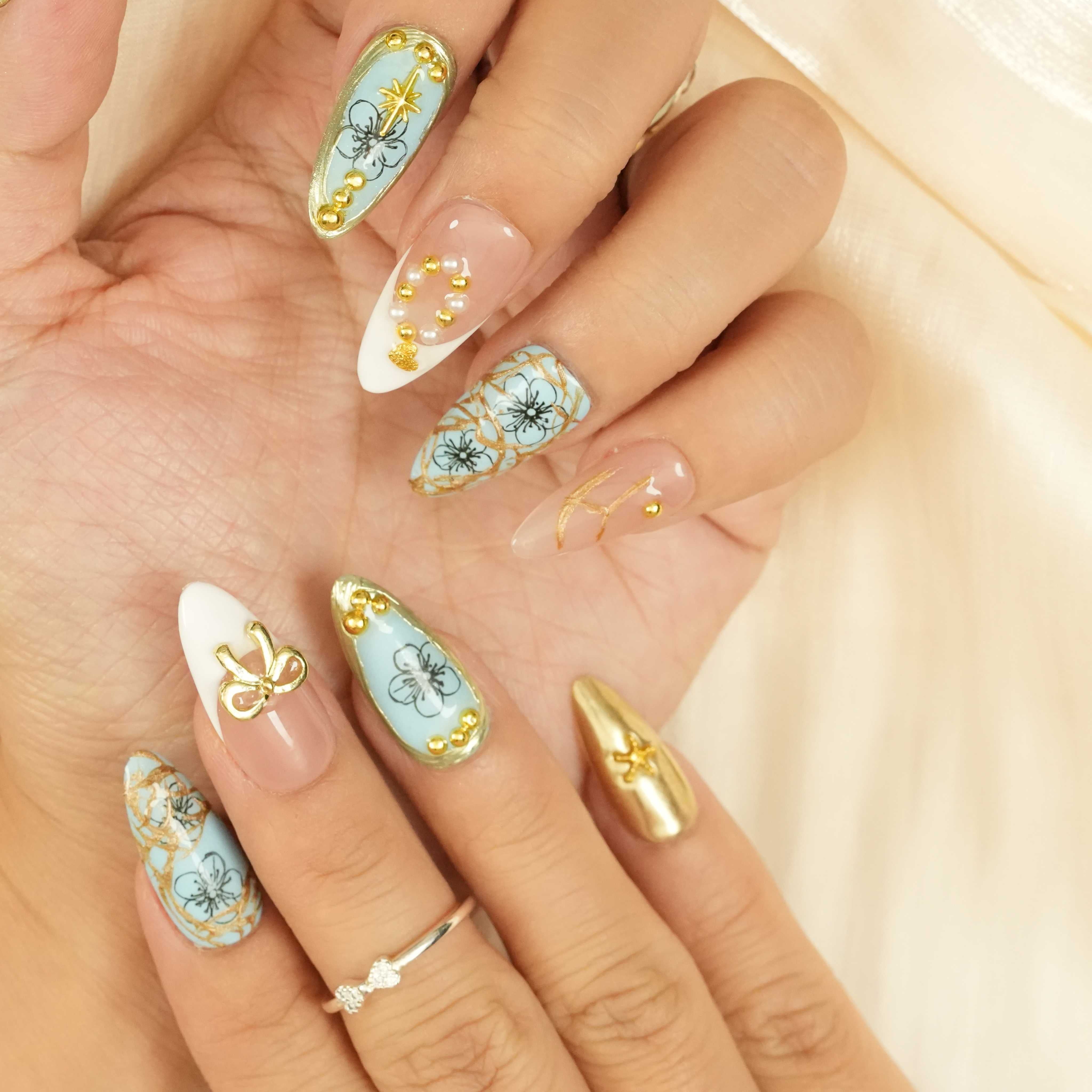 Side view showing blue and gold press on nails with delicate flower and chain accents
