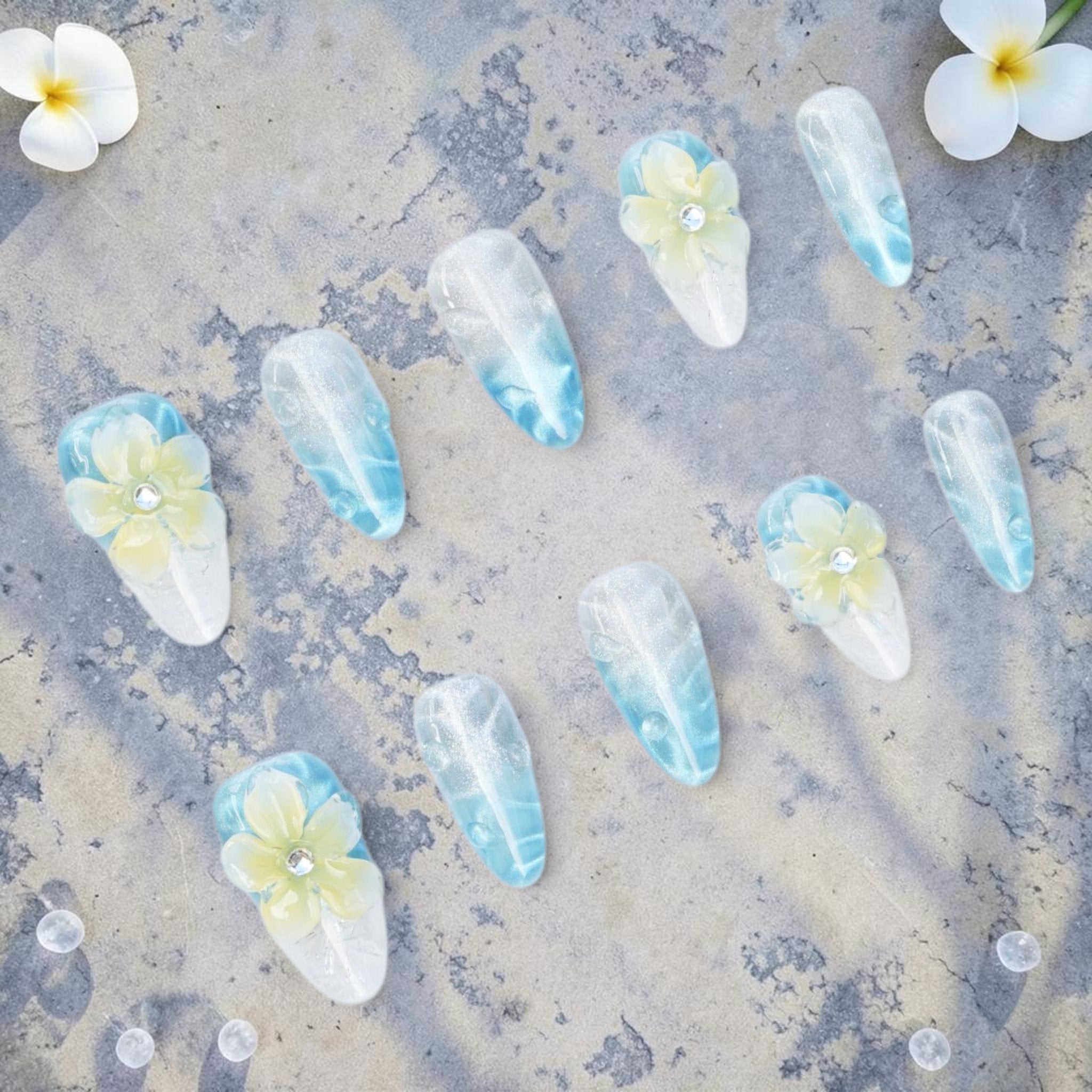 DSC00032 frangipani press on nails full set with 3D flowers on an ocean blue cat eye base laid flat