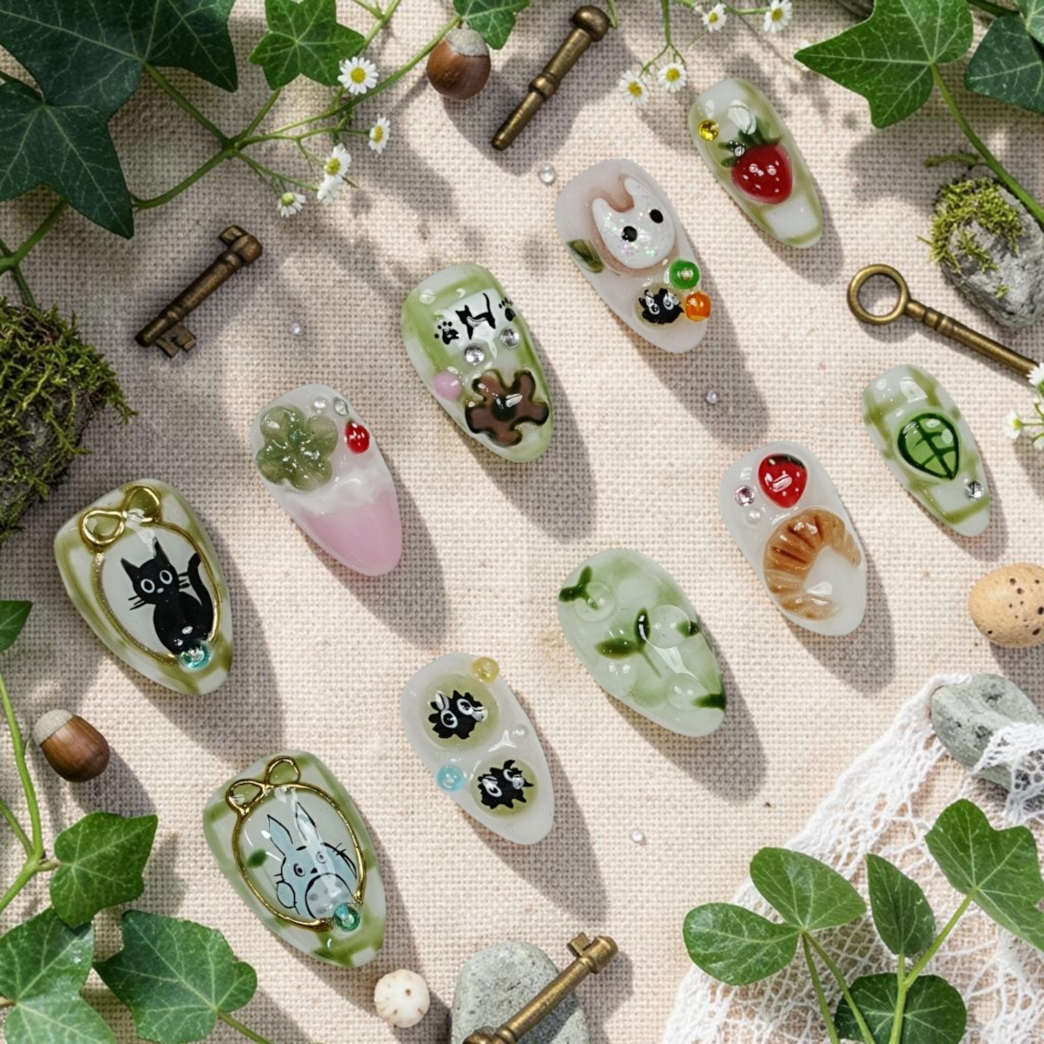 DSC00047 matcha press on nails full set in green and cream with cute forest characters, 3D strawberries and a croissant laid flat