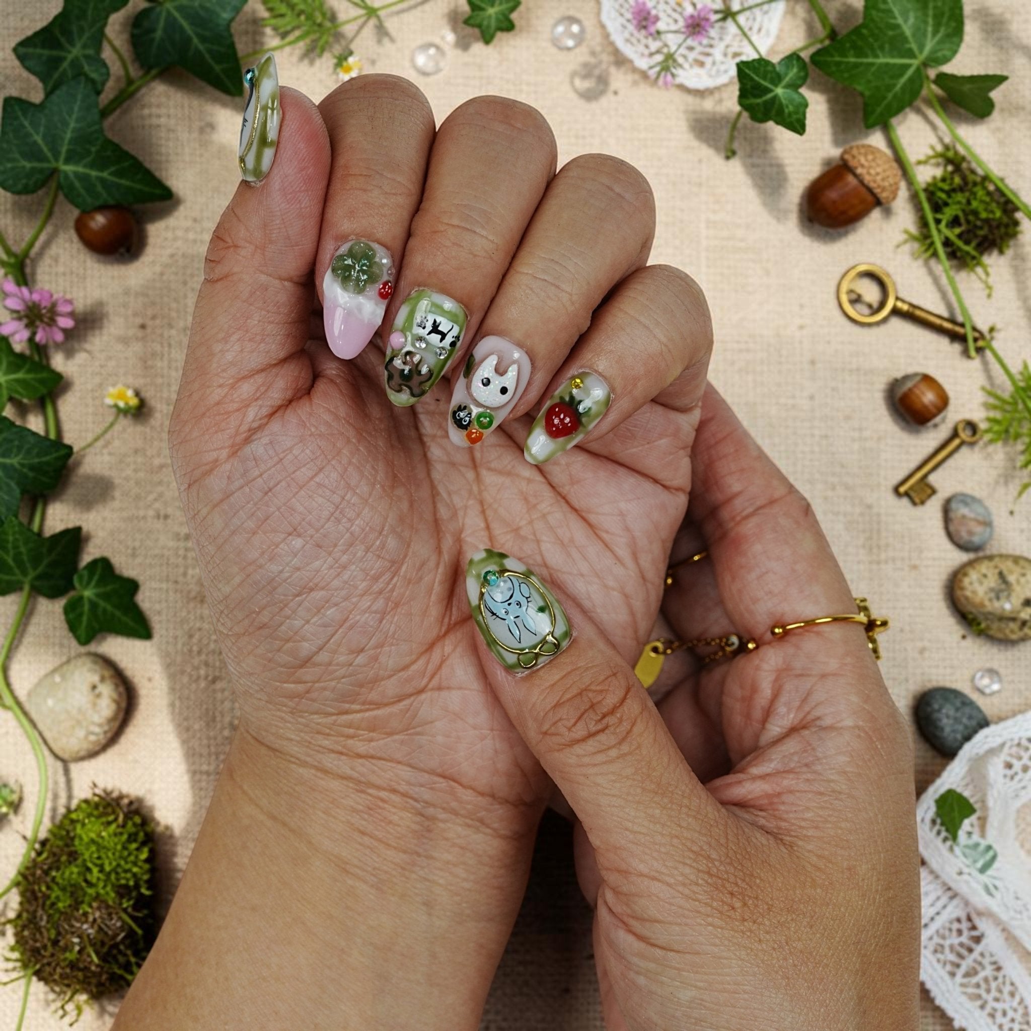 DSC00051 two hands showing matcha woodland press on nails with fuzzy black character friends and a four leaf clover