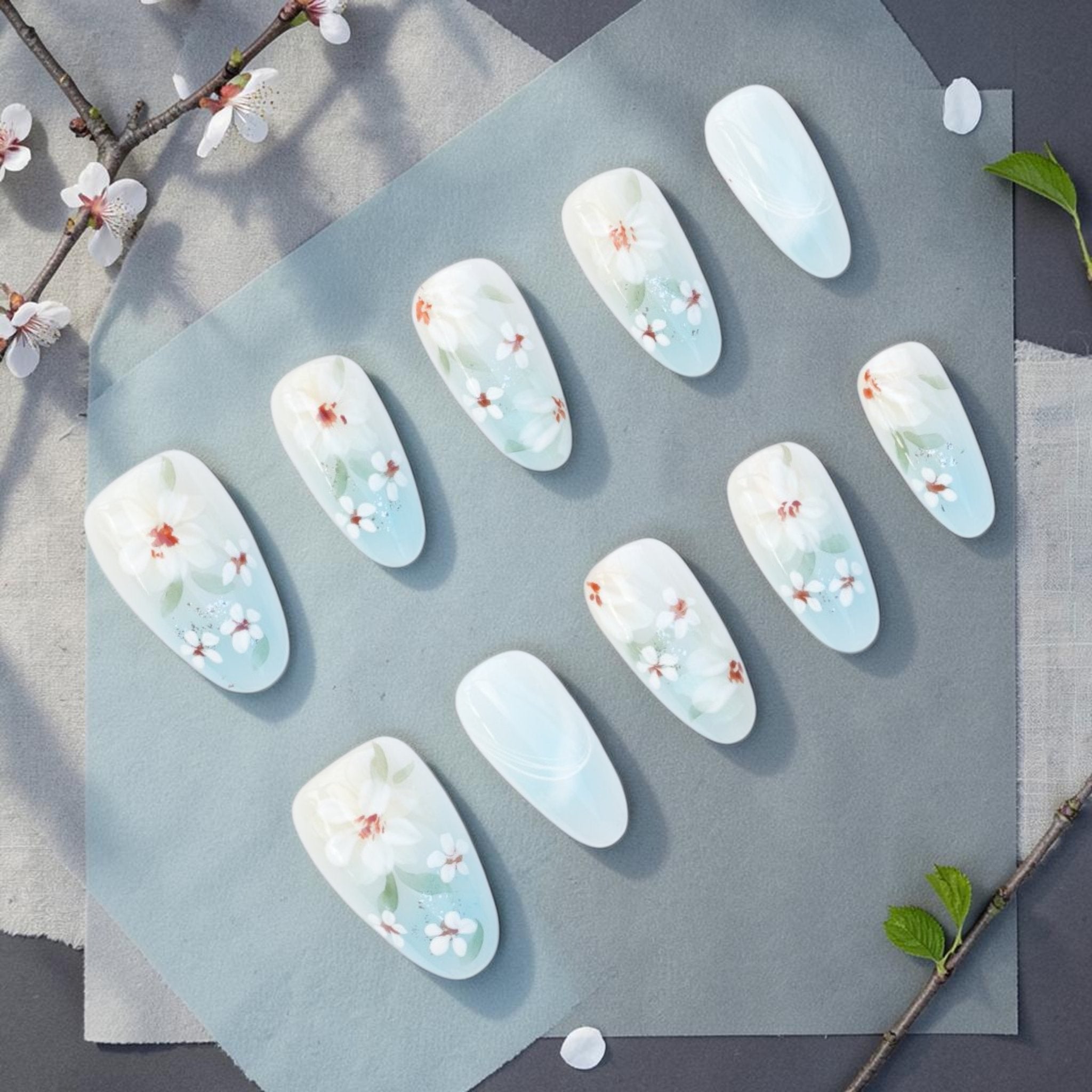 DSC00052 white floral press on nails full set with painted blossoms on a milky blue base laid flat