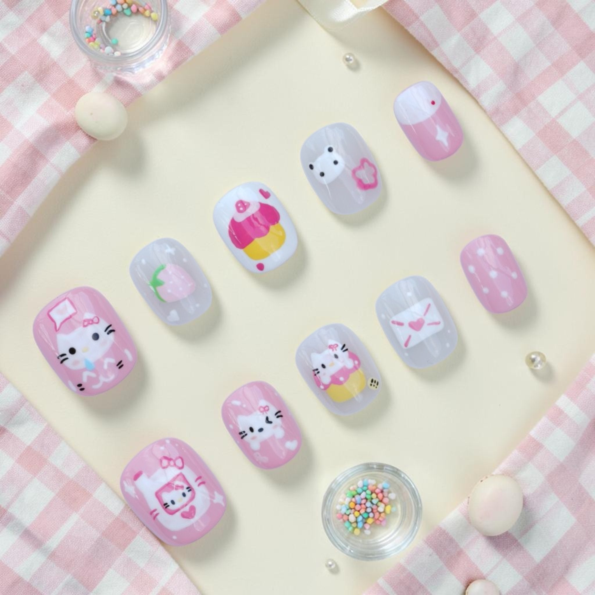 Handmade cute cat press on nails flat lay in pink and white with kittens, cupcakes, strawberry and love letters
