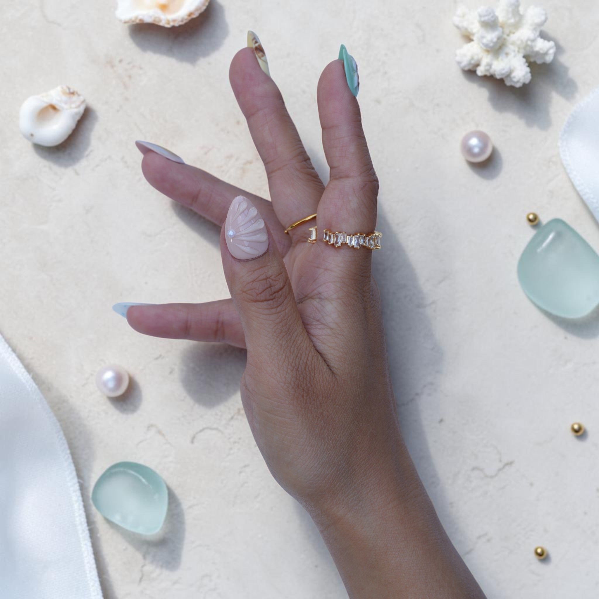 Almond ocean press on nails with sculpted shell, pearls and gold foil detail on hand