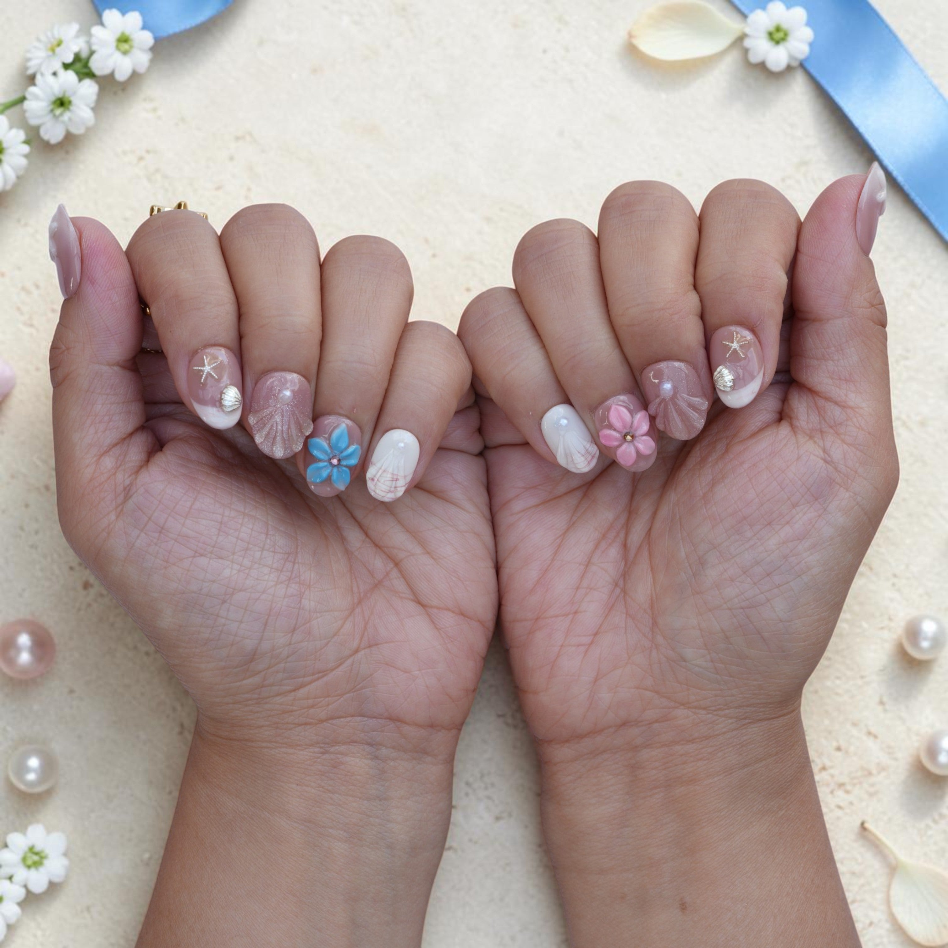 Pearl Lagoon press on nails shown on both hands in pink, cream and pearl coastal design