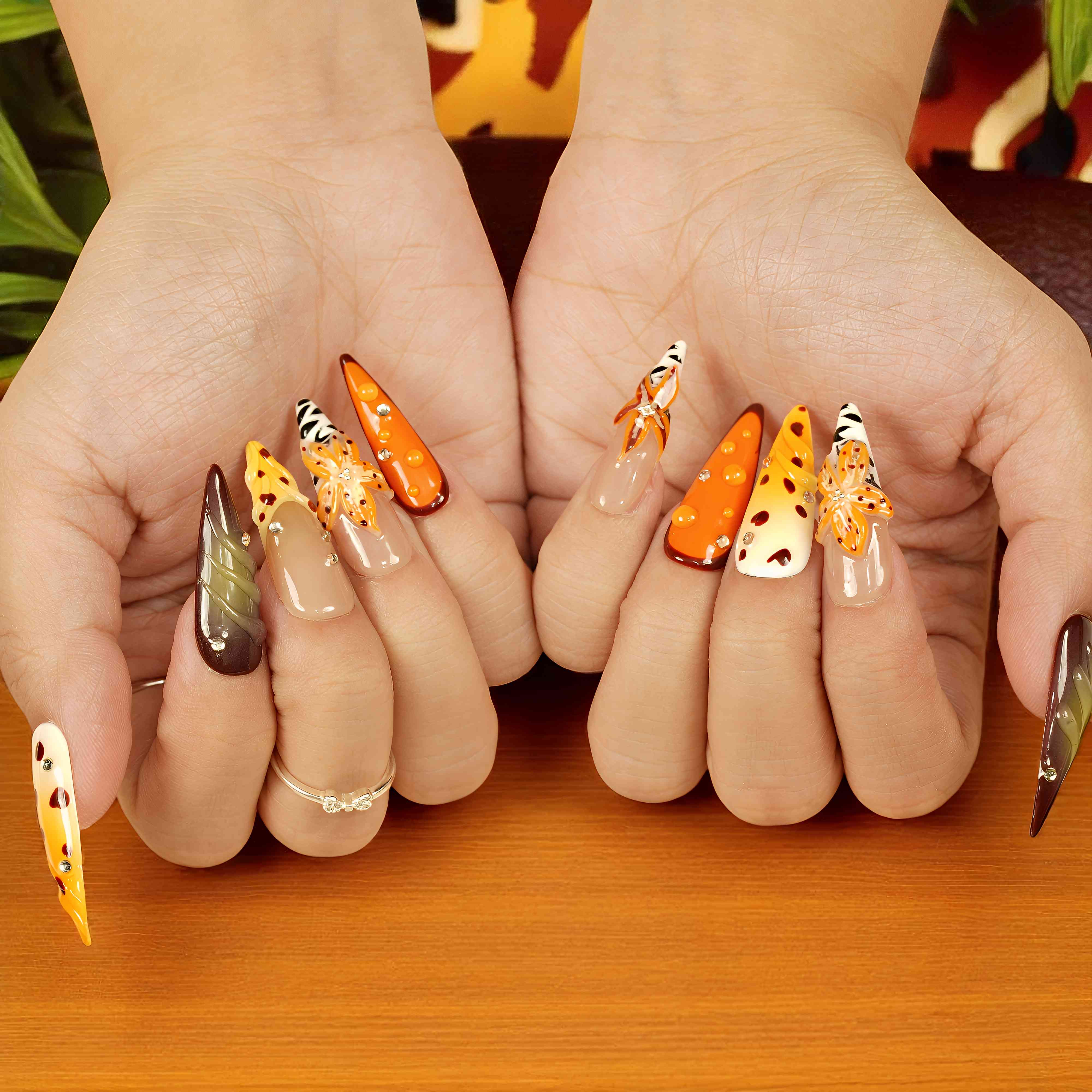 press on nails with animal print and 3D orange flowers styled on hand