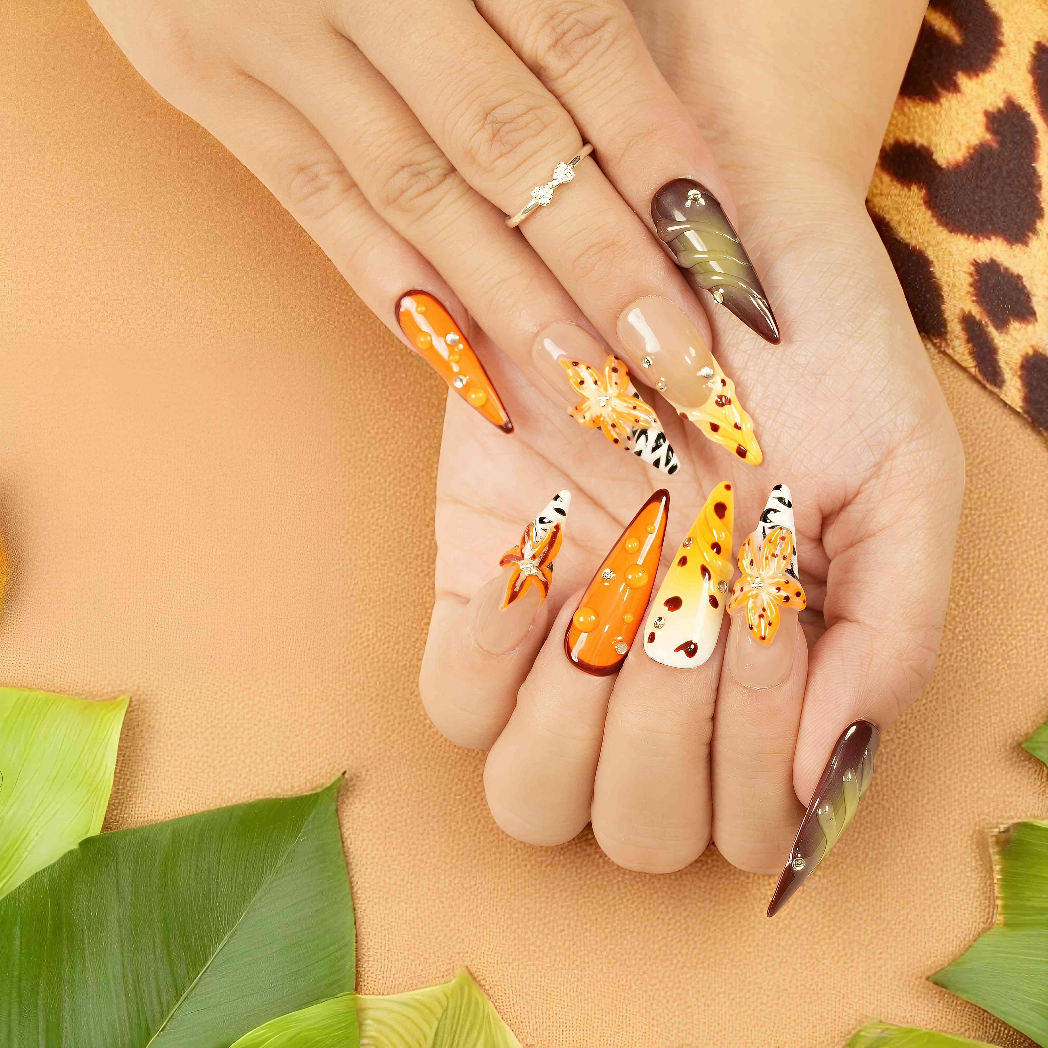 closeup hand pose showing reusable press on nails with orange rhinestones