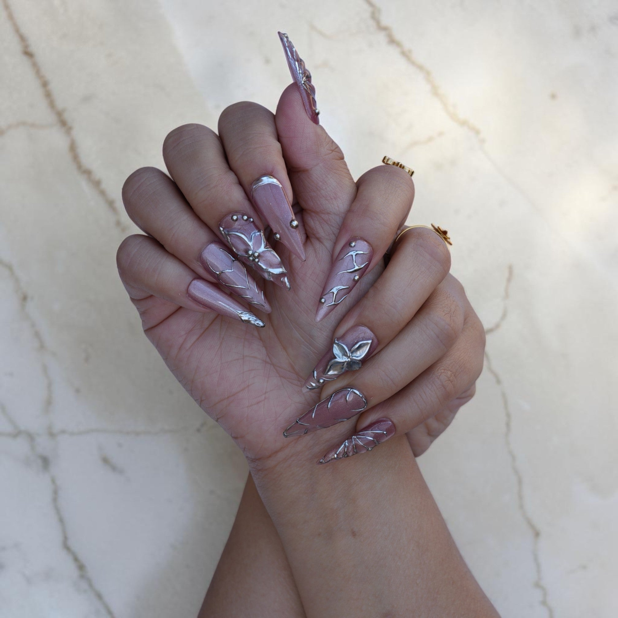 Both hands wearing Silver Fae stiletto press on nails with silver flower art