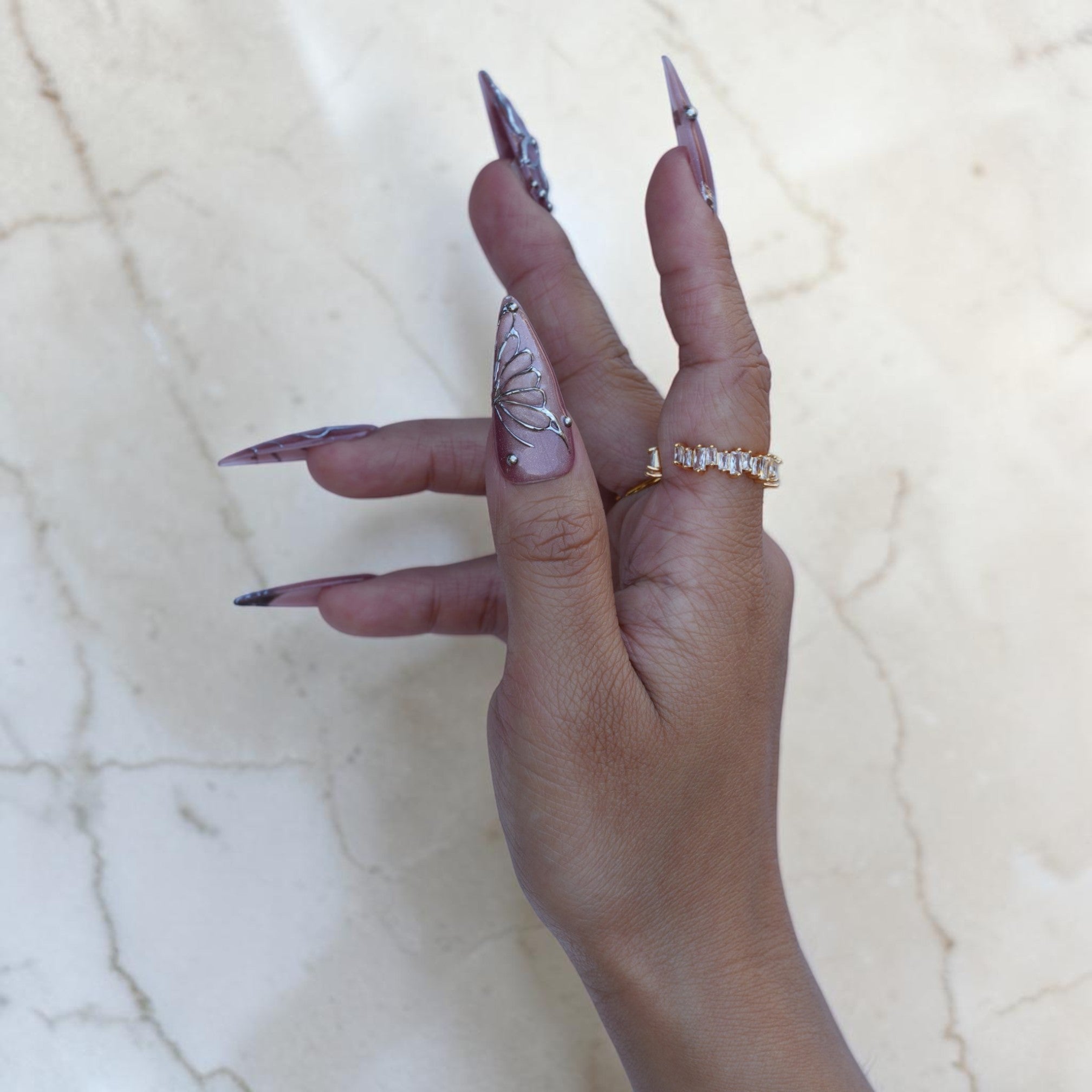 Hand wearing Silver Fae mauve stiletto press on nails with silver butterfly wing art