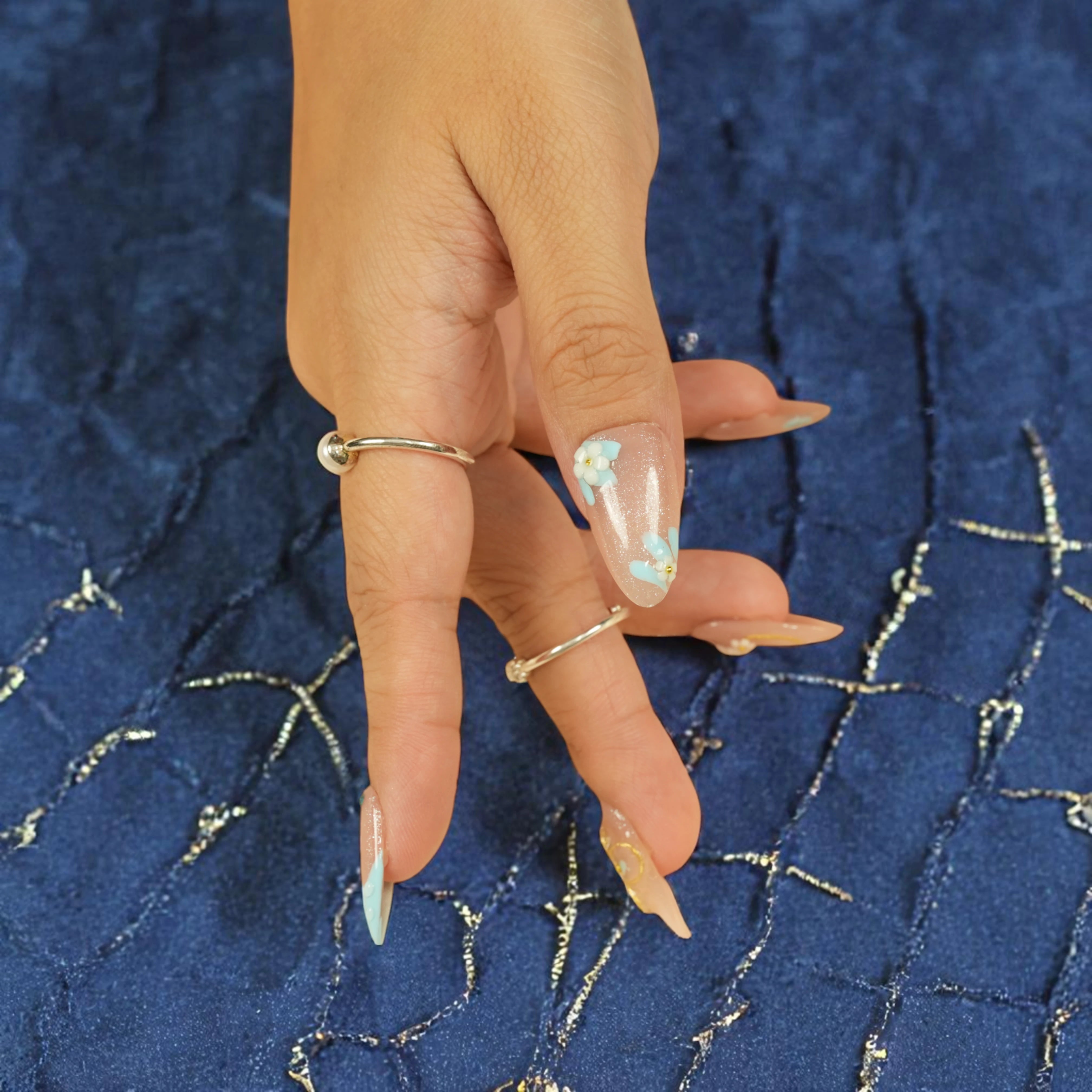 Elegant artificial nails with French tips, glitter, and pastel flowers for soft glam look