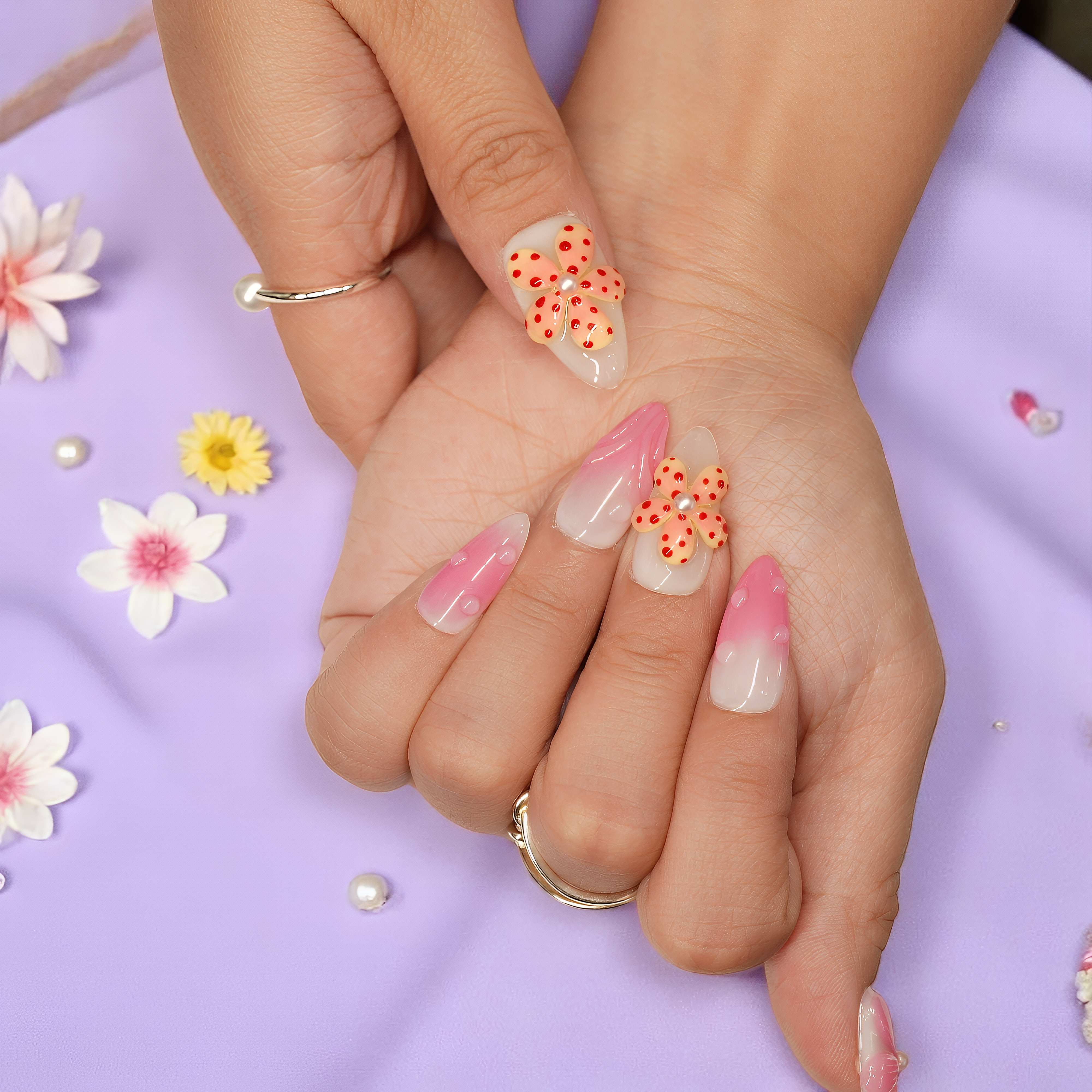 Thumb and index finger with orange polka dot flower press on nails from the Petal Pop collection