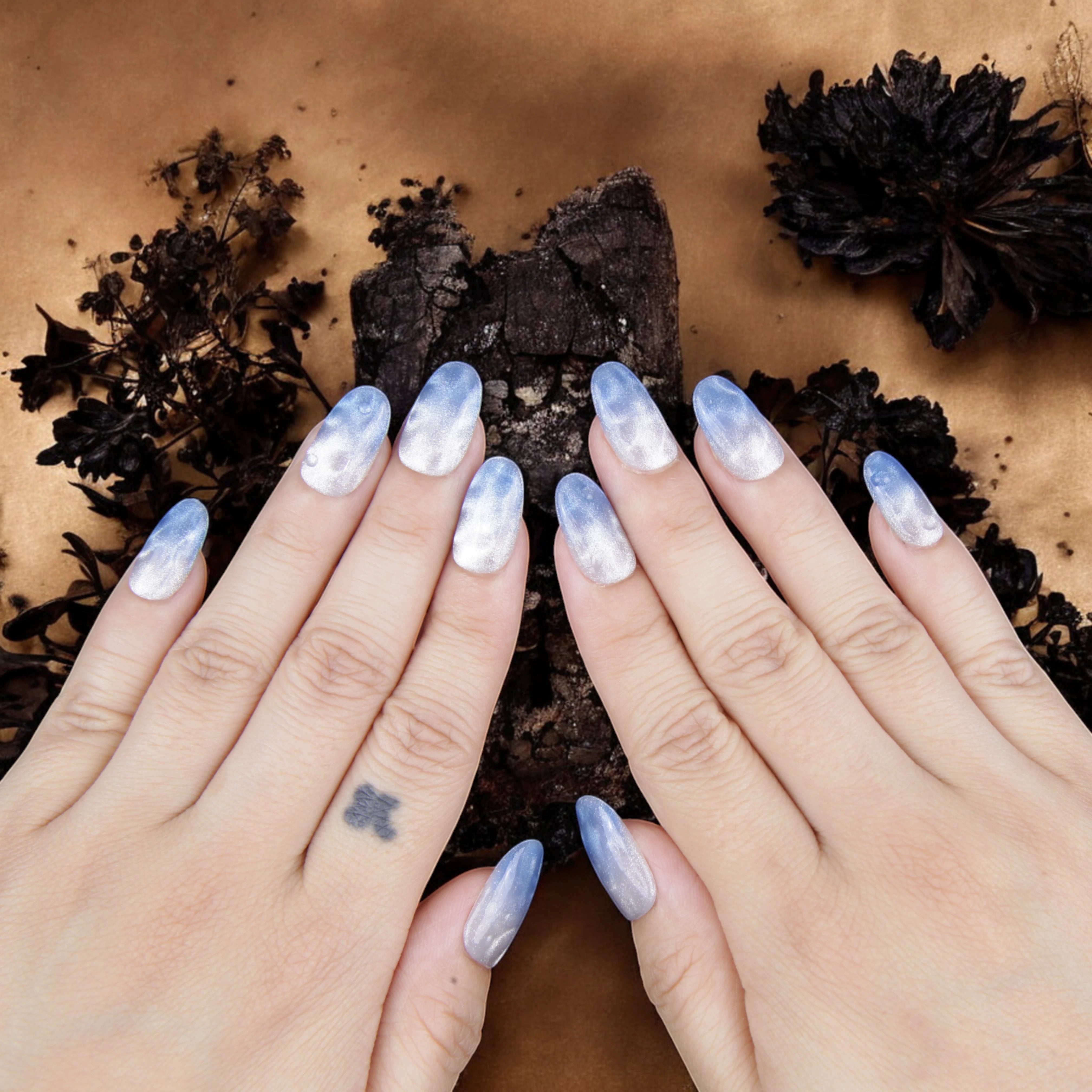 Hand model wearing blue ombre false nails, reflecting a summer beach wave aesthetic with a glossy water effect