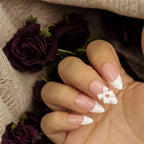 Almond-shaped French press on nails with 3D white flower design, styled on hand with deep purple roses – handmade stick on nails Australia