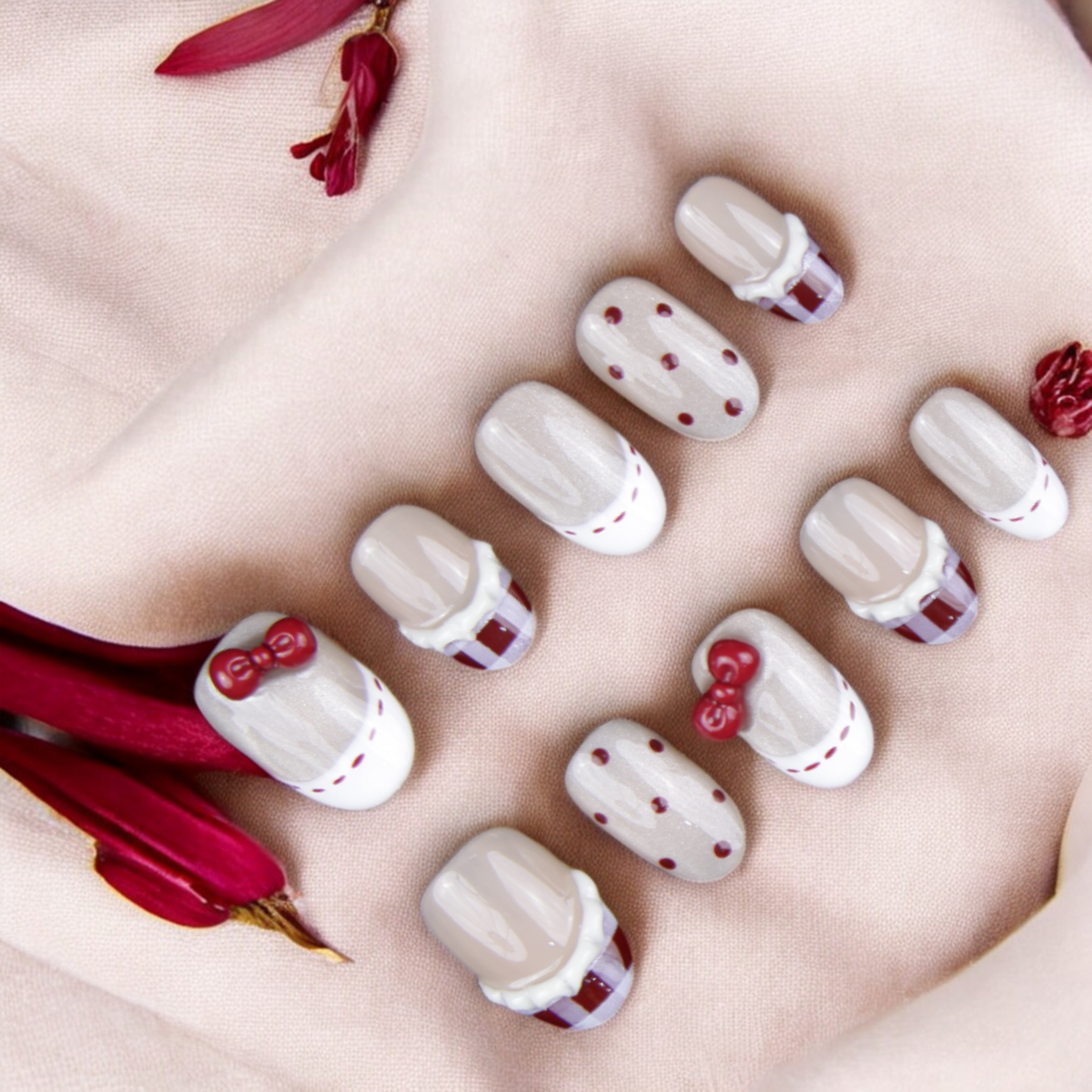 Chic vintage-inspired artificial nails in soft nude with red bow and plaid details. Perfect for an elegant, timeless nail set