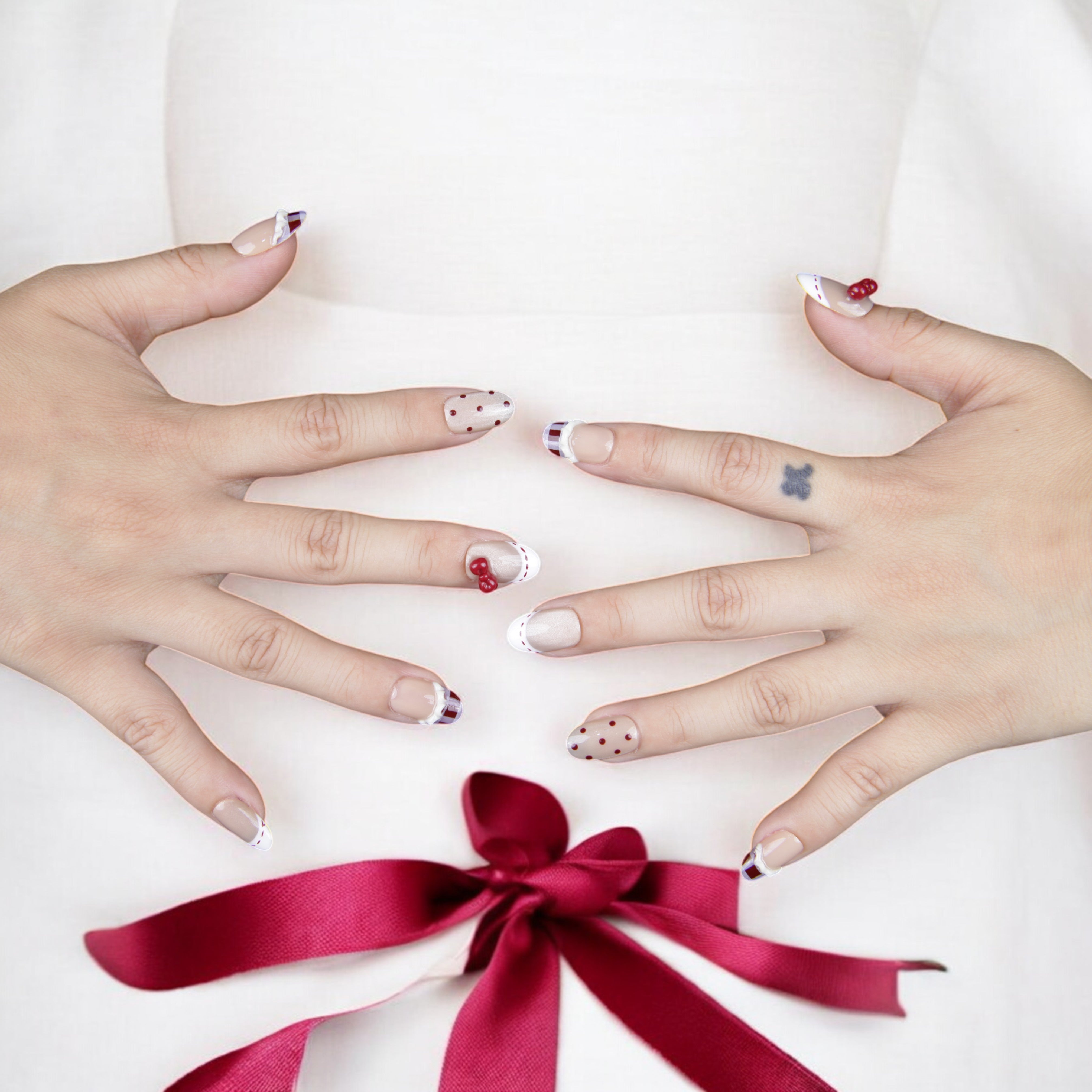 Stylish glue-on nails in a nude and red ribbon-inspired design. A perfect blend of classic elegance and modern nail fashion