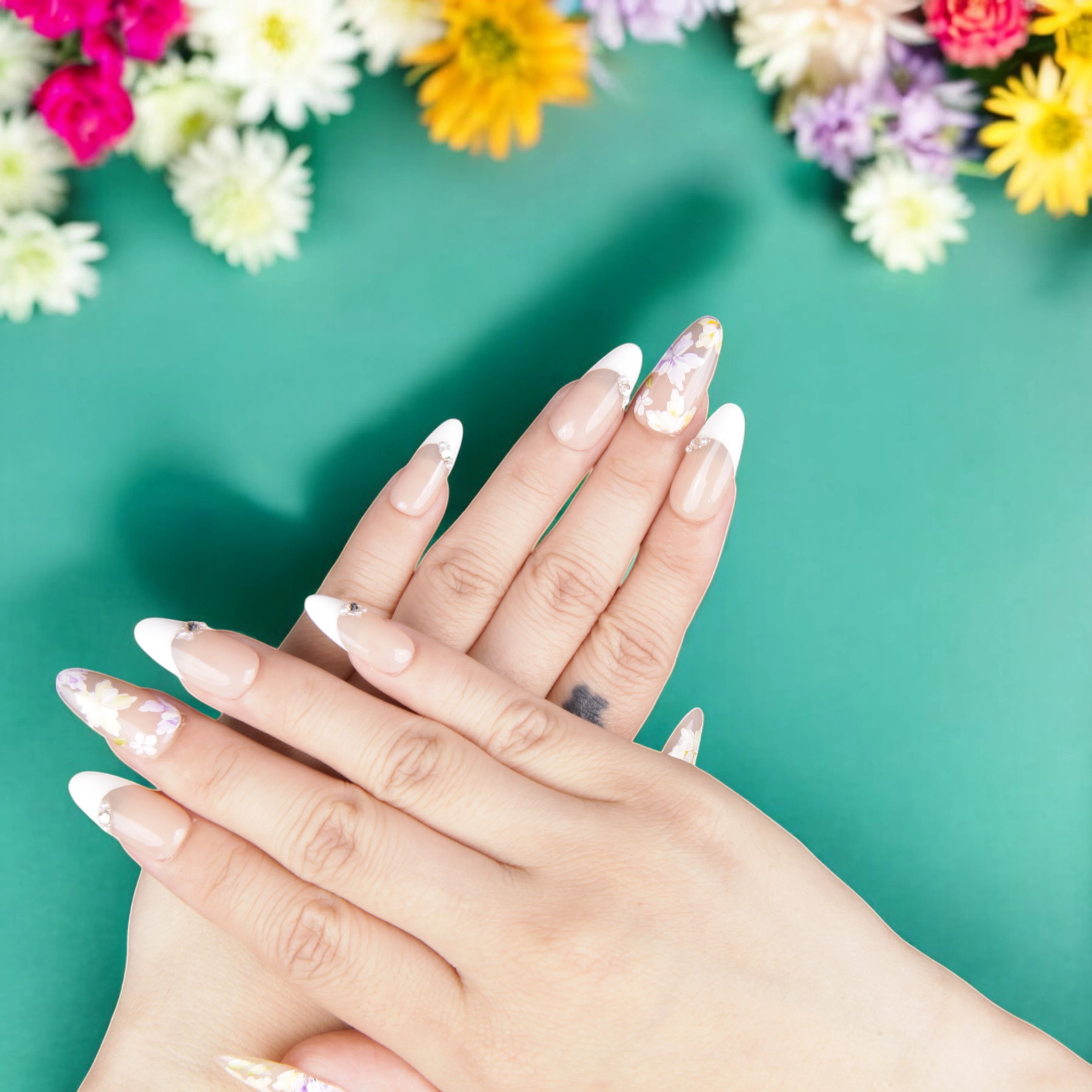 Delicate floral French tip press on nails displayed with blooming flowers, capturing a fresh and elegant springtime nail aesthetic.
