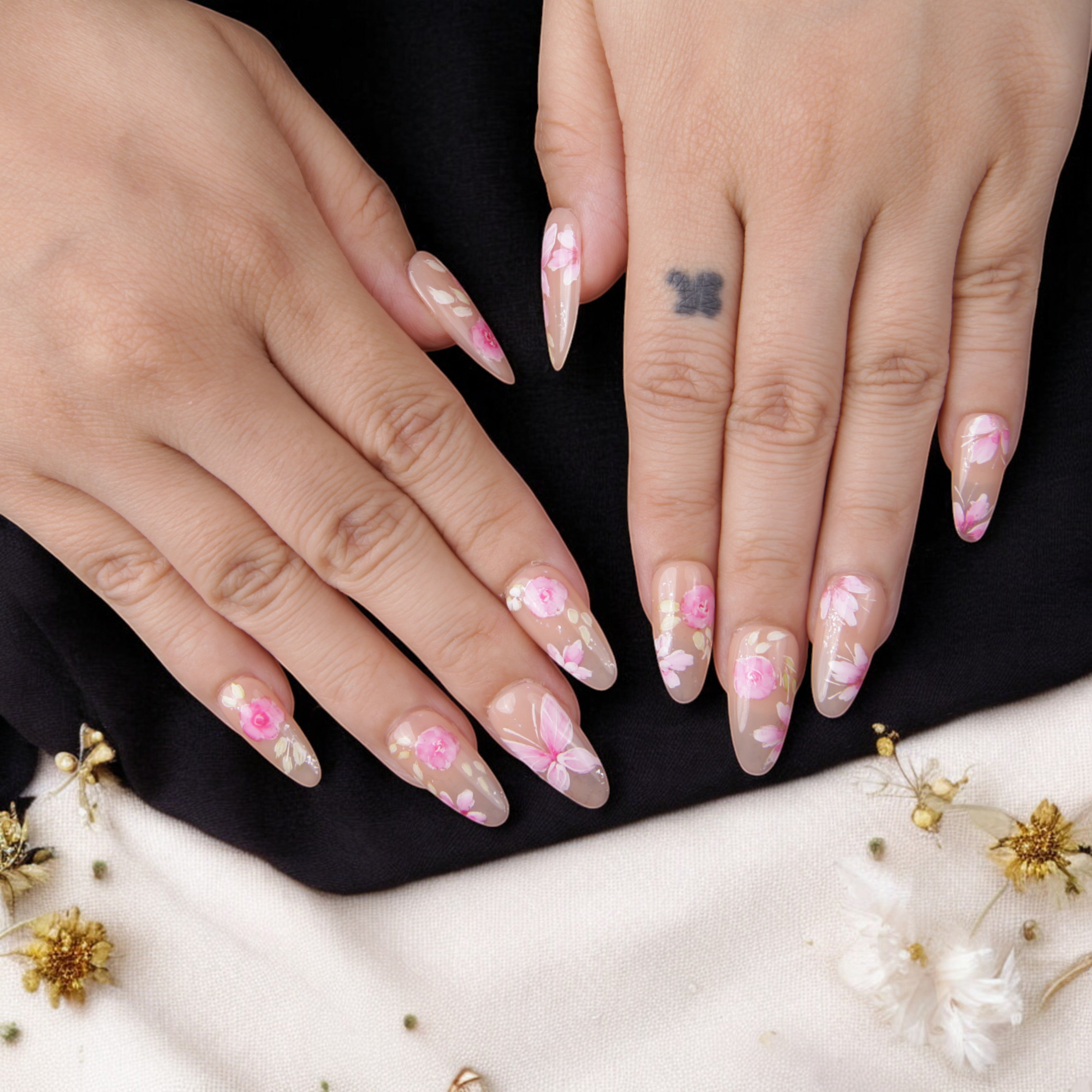Hand-painted floral glue-on nails in a natural almond shape, featuring delicate pink and white flowers for a timeless manicure.