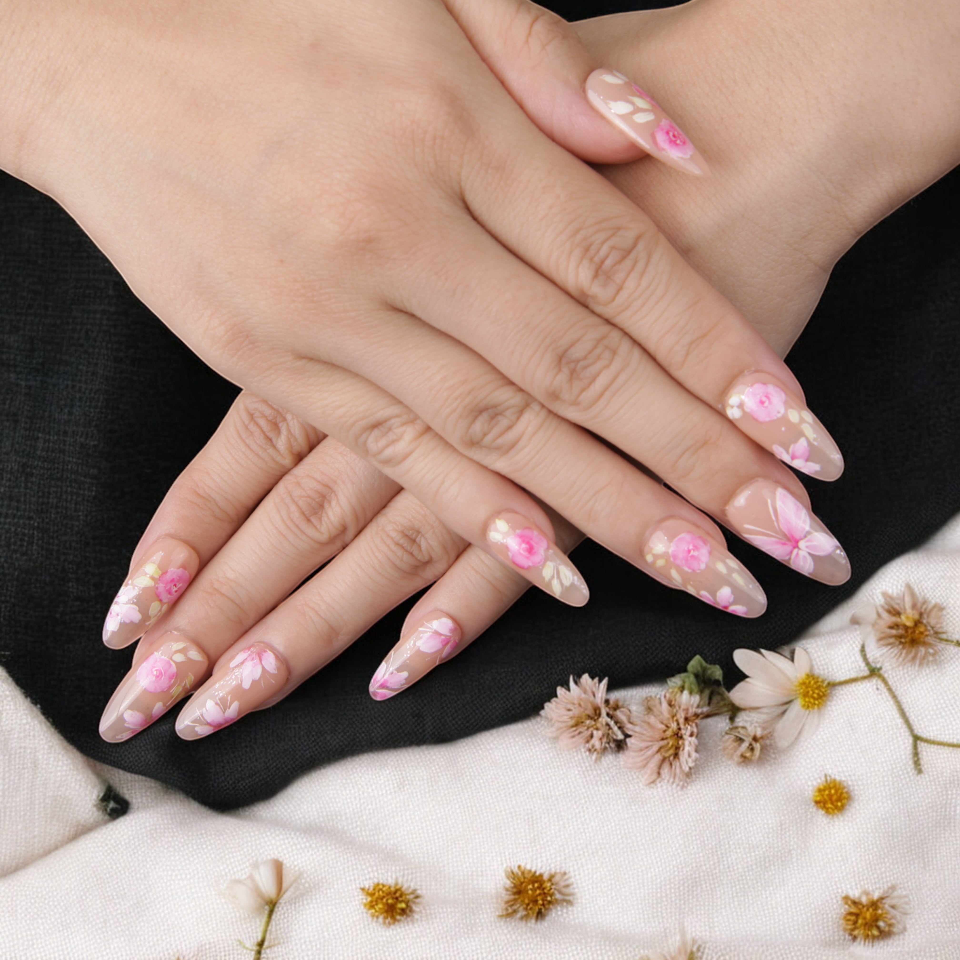 Stylish long almond-shaped adhesive nails with a hand-painted floral motif, giving a refined and natural nail extension look.