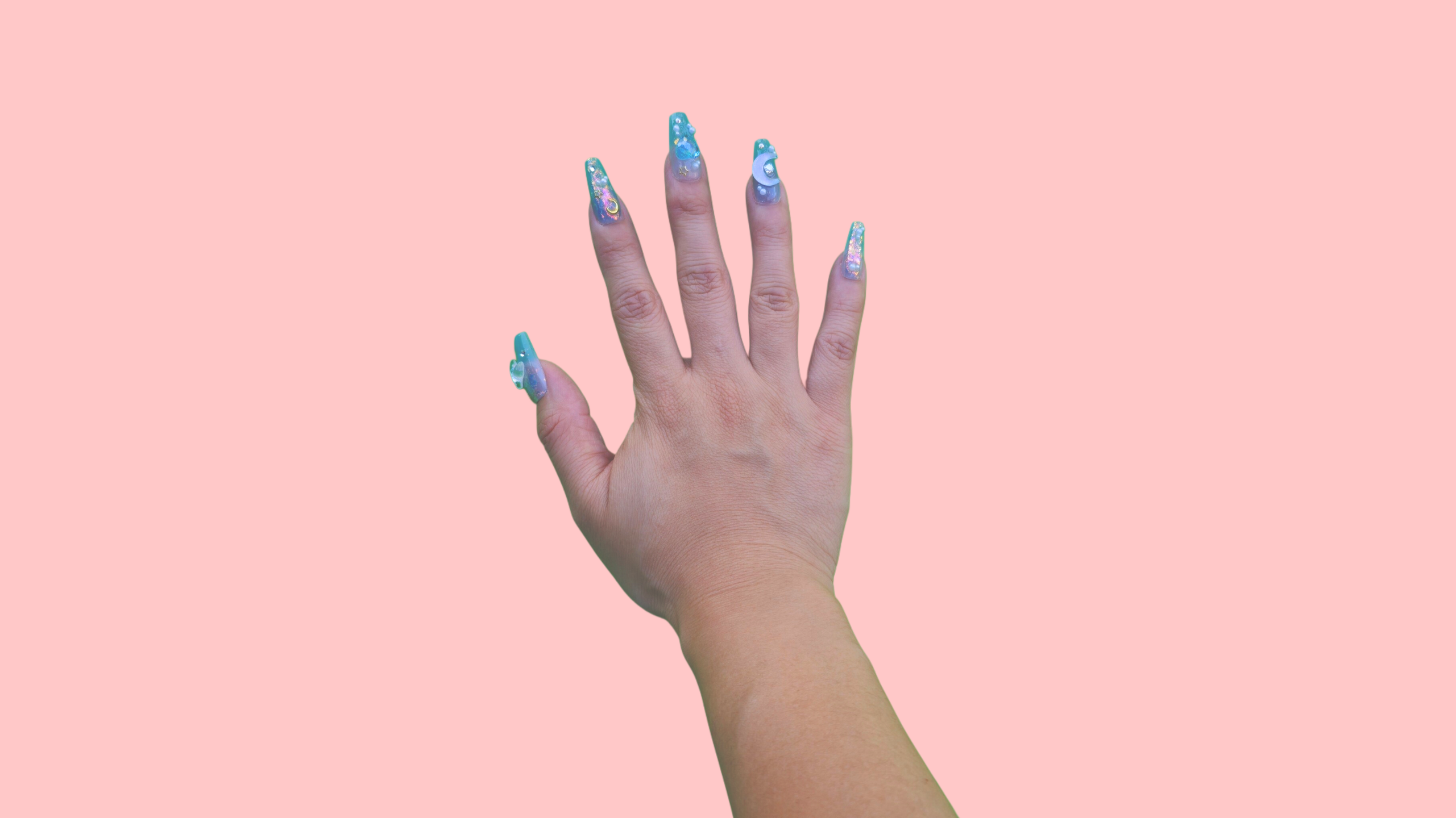 Finished press on nails set with 3D embellishments and glitter detail, shown on hand against pastel pink background — transformation result.