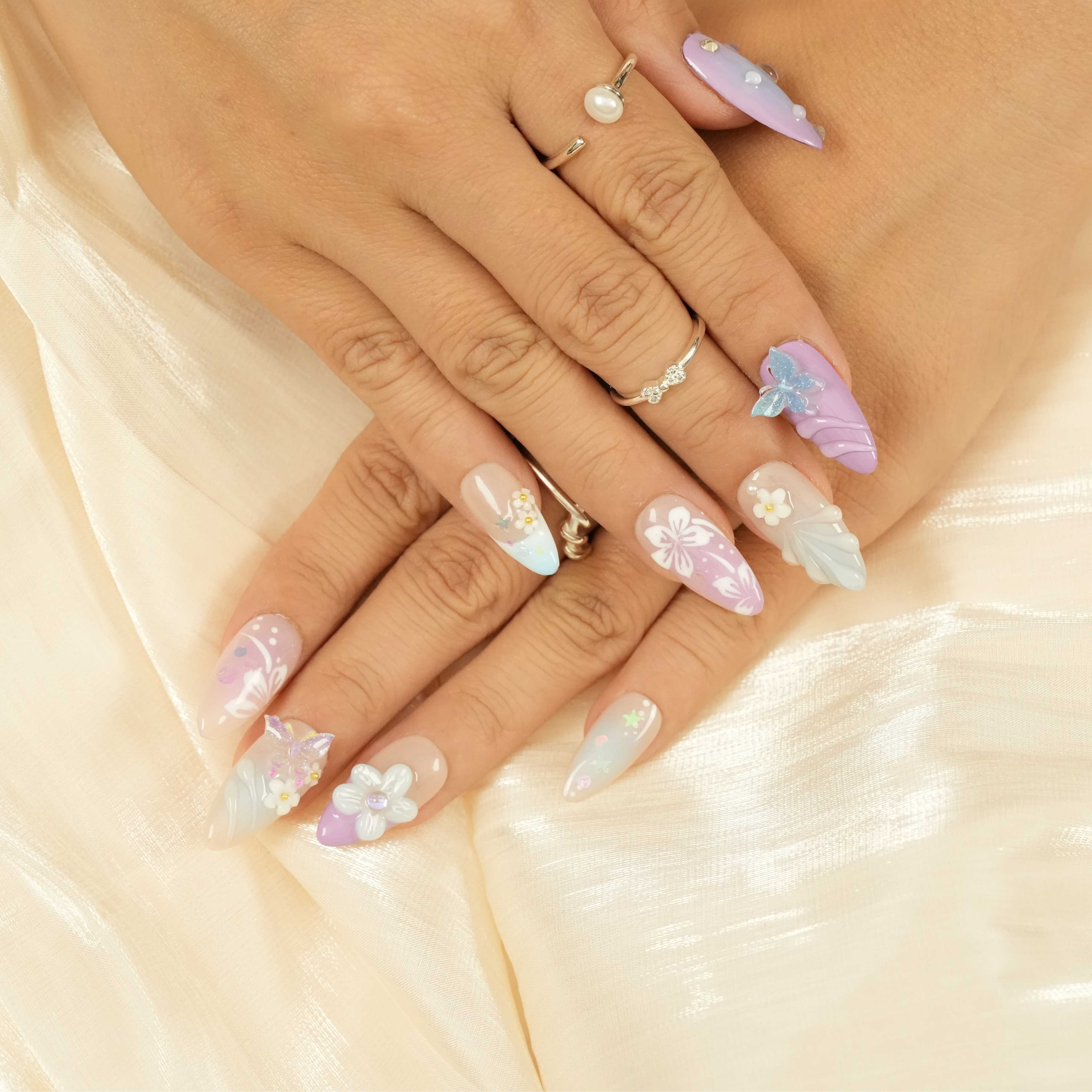 Complete press on nails set featuring butterflies, pastel florals, and pearl designs on almond-shaped artificial nails. Perfect for fashion and lifestyle looks