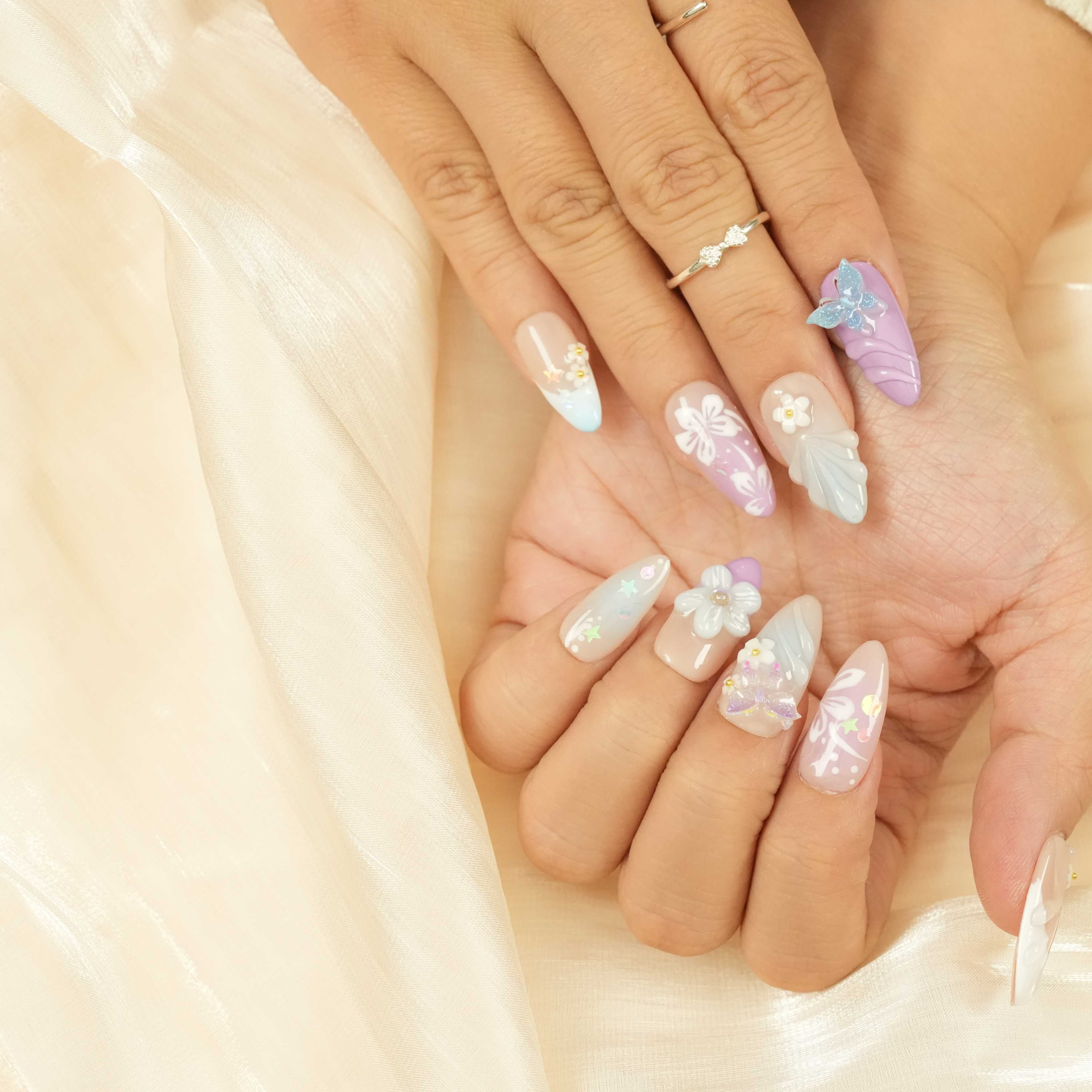 Handcrafted press on nails featuring pastel florals, butterflies, and pearlescent glue on nails for a dreamy, elegant look