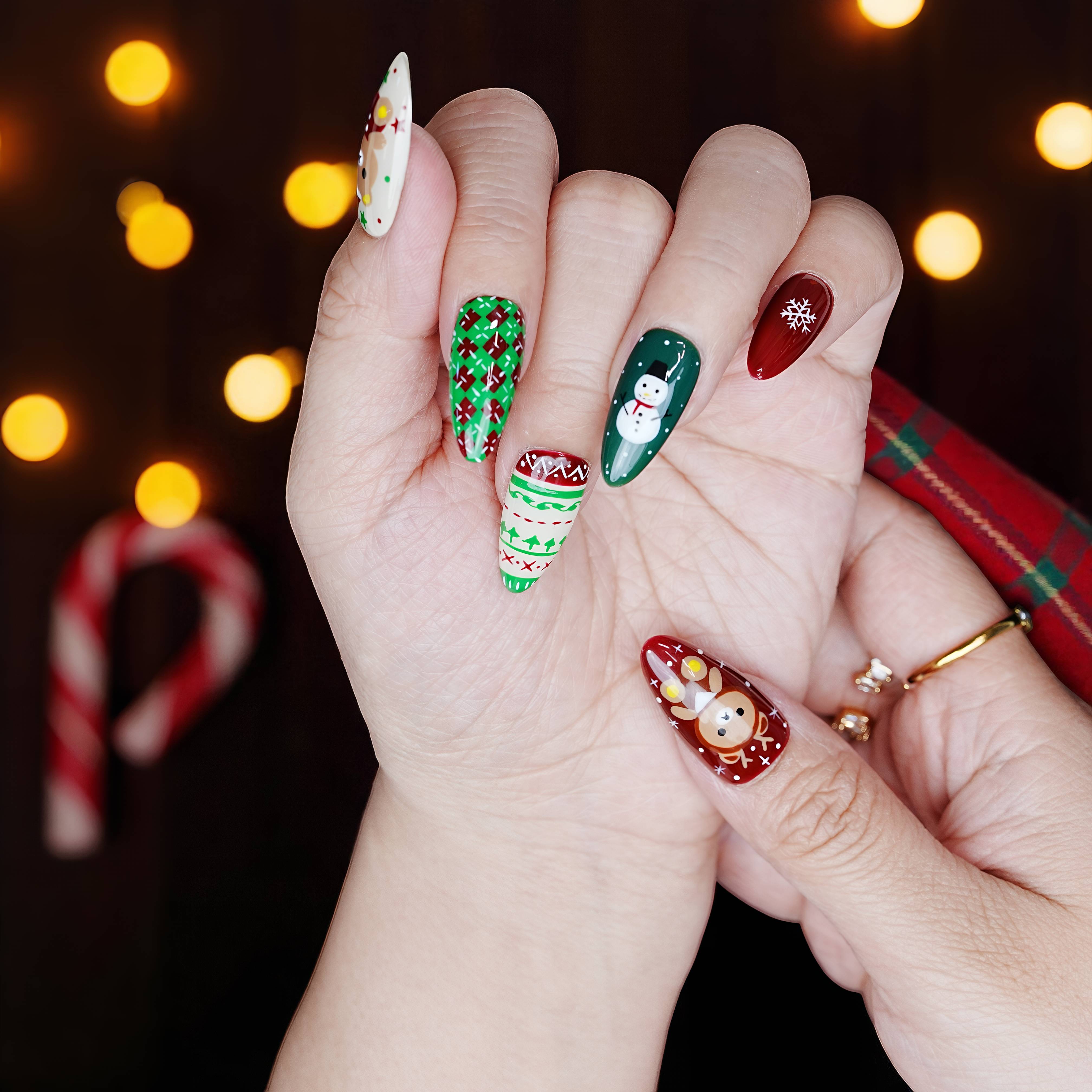 Holiday nail set in hand pose showing candy cane stripes, gingerbread details, and green sweater textures.