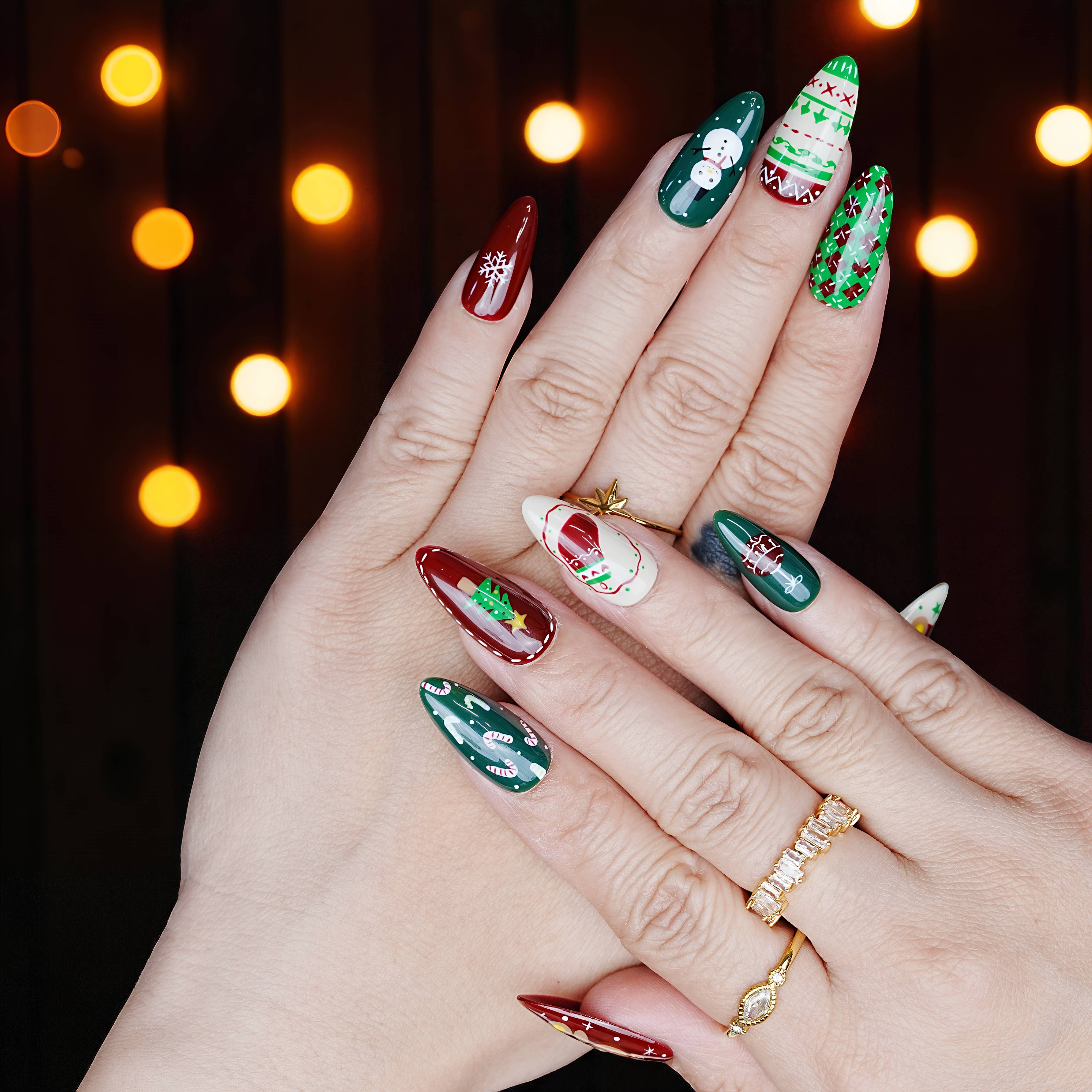 Both hands showing full nail set in holiday lighting, featuring green knits, red accents, and Santa heads.