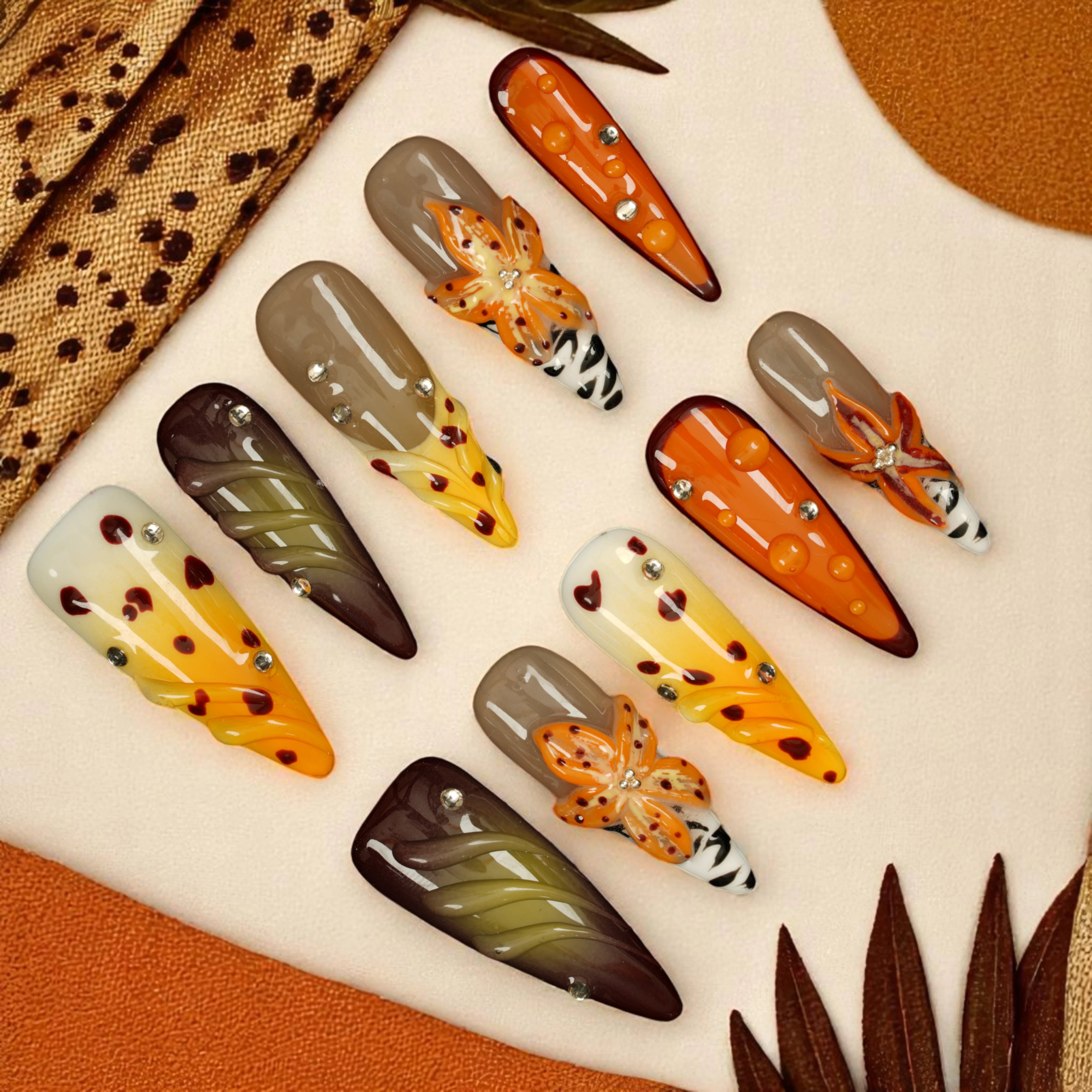 orange wildflower press on nails with zebra stripe accents and rhinestones on neutral base