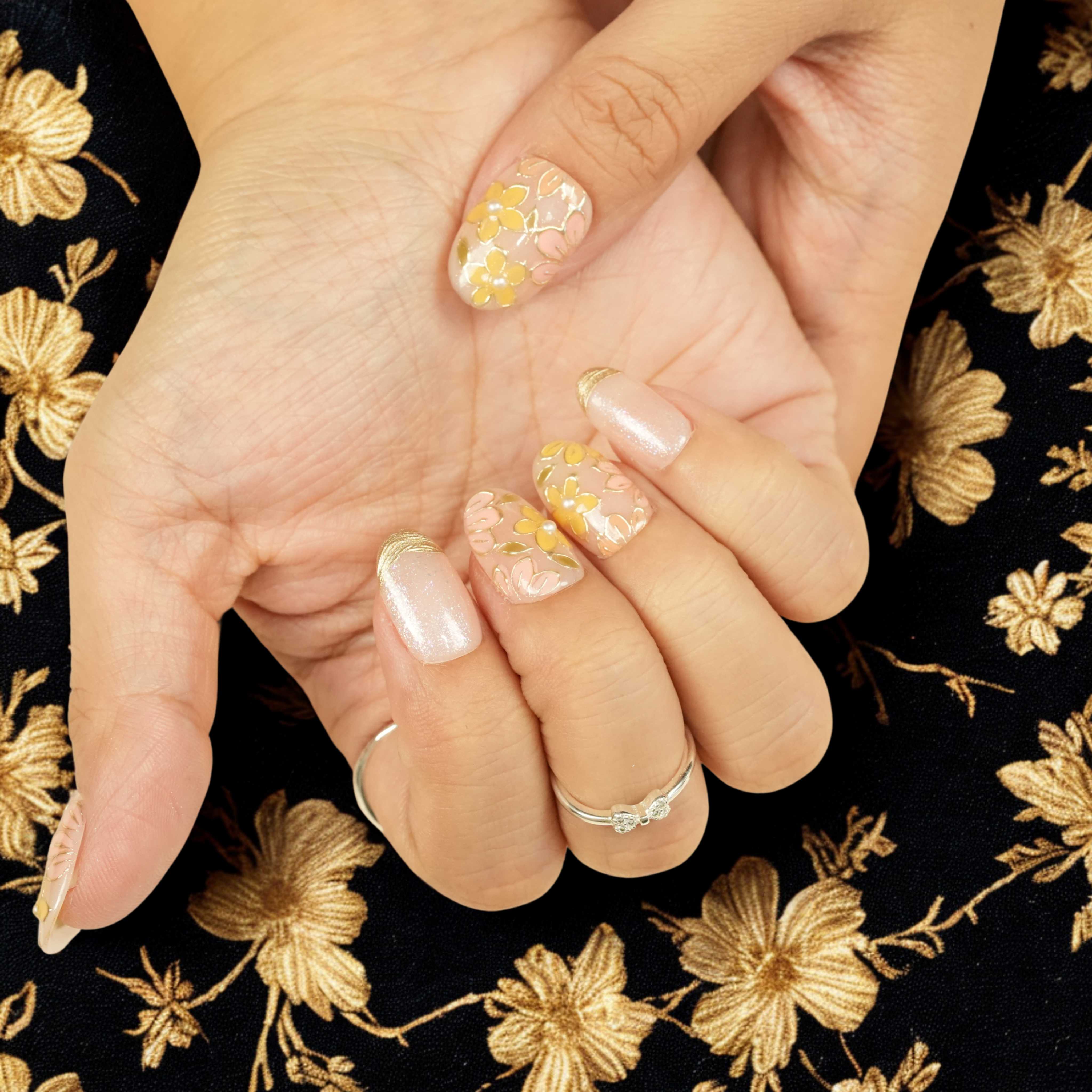 Short almond press on nails Australia featuring delicate yellow flowers, gold accents, and shimmer details, styled with silver rings