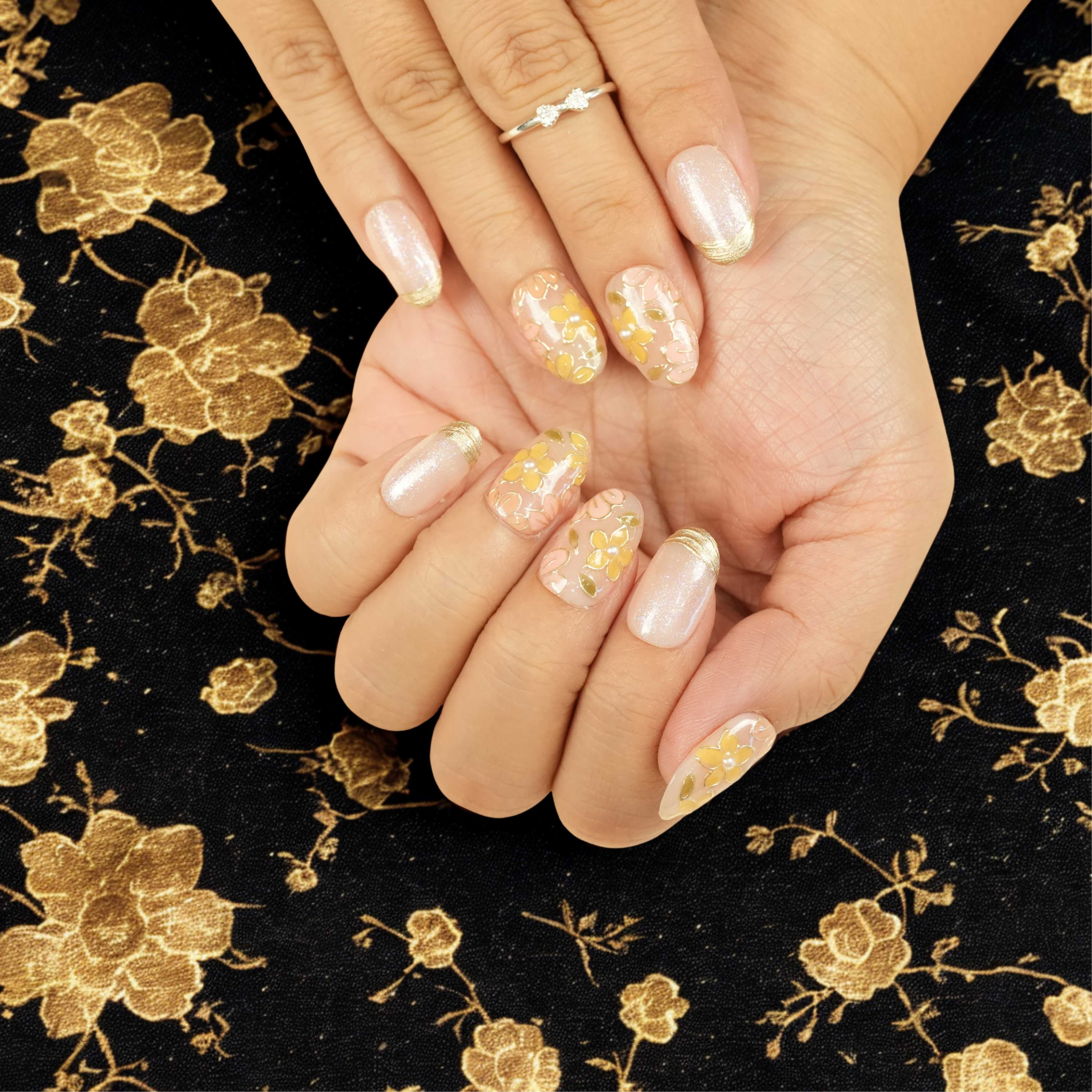 Reusable press on nails with golden floral patterns and pearlescent shimmer, ideal for elegant lifestyle and fashion styling