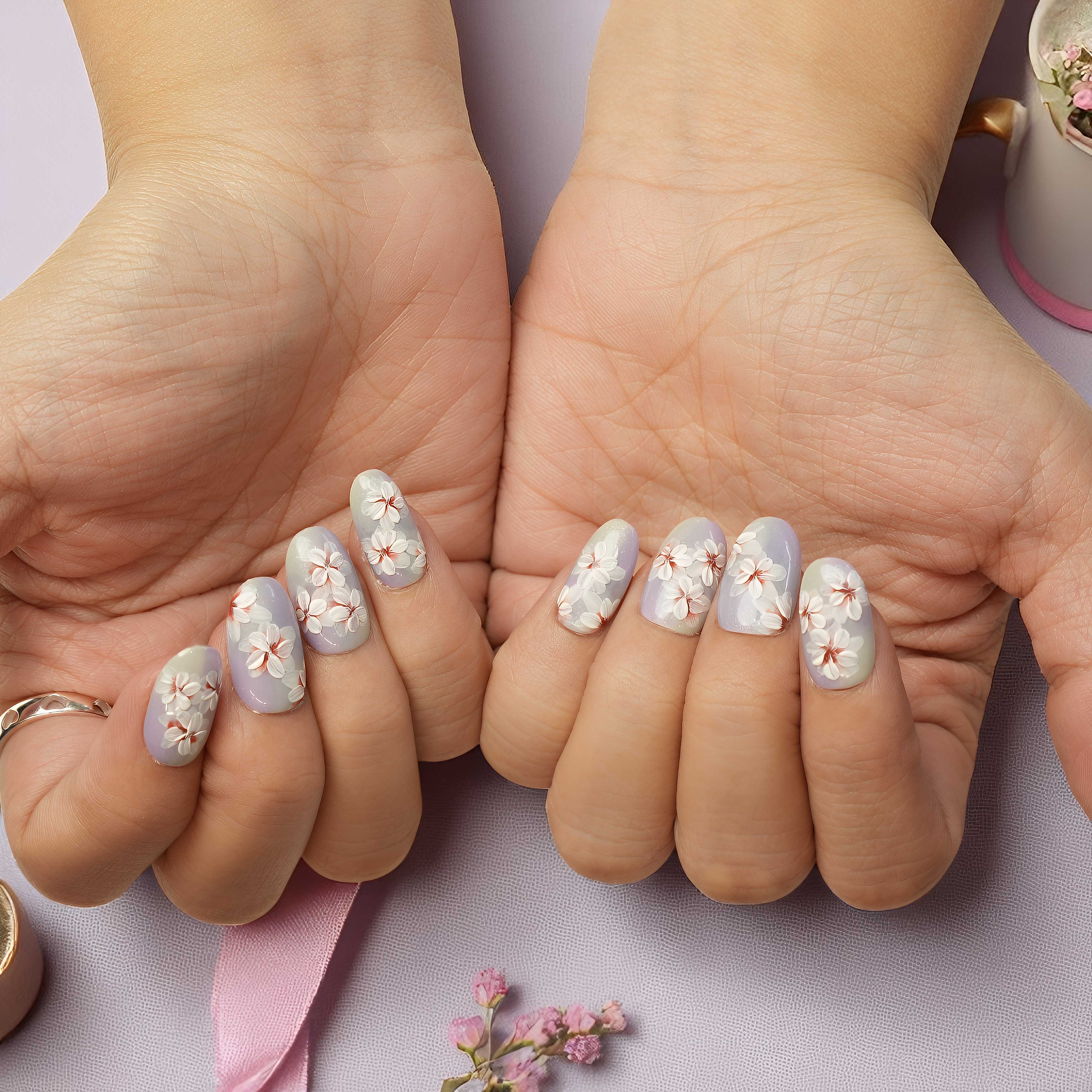 Close-up of hands with floral nail design on a light background