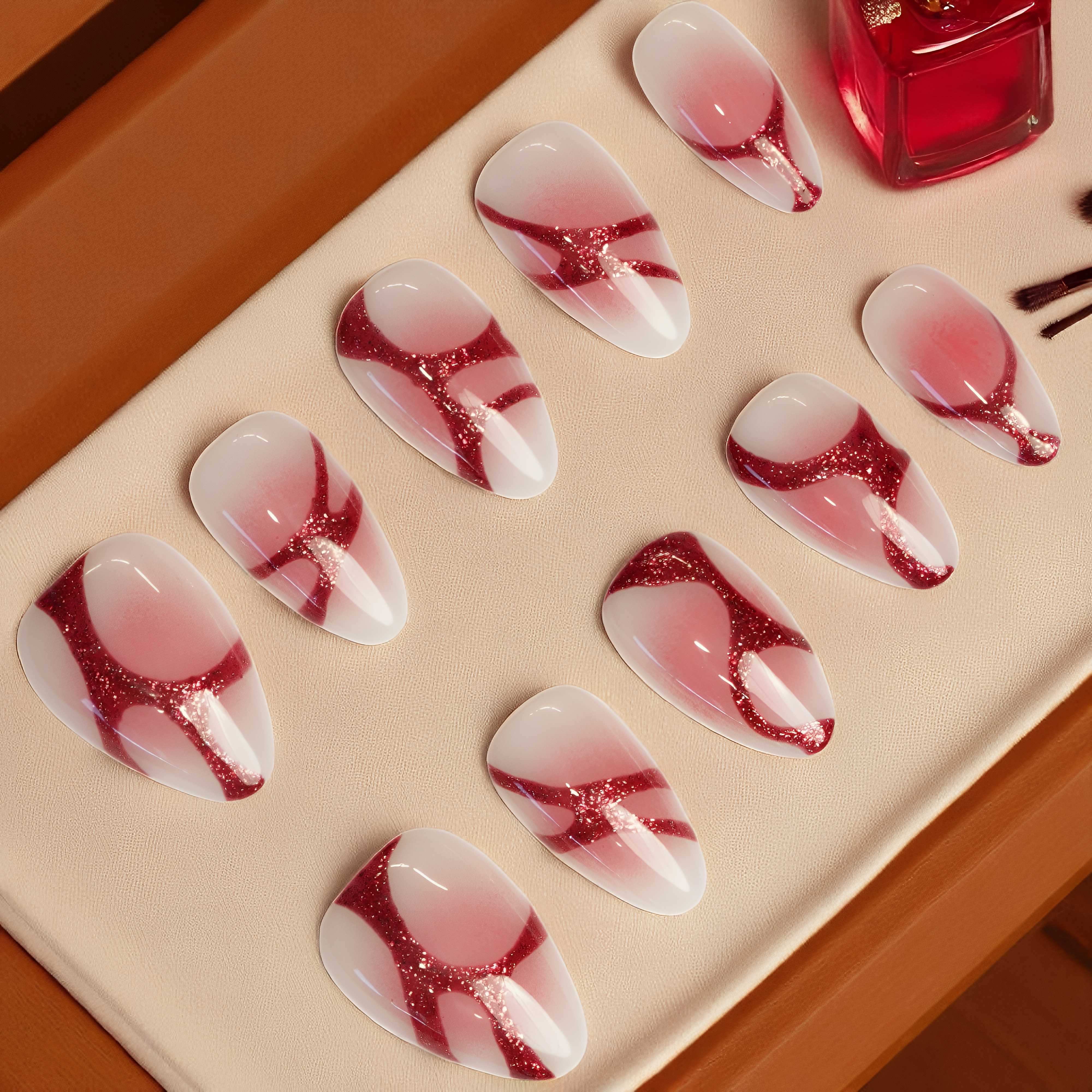 Full layout of Crimson Swirl Rush nail set — 10 artificial nails in red and pink abstract design displayed on white background.