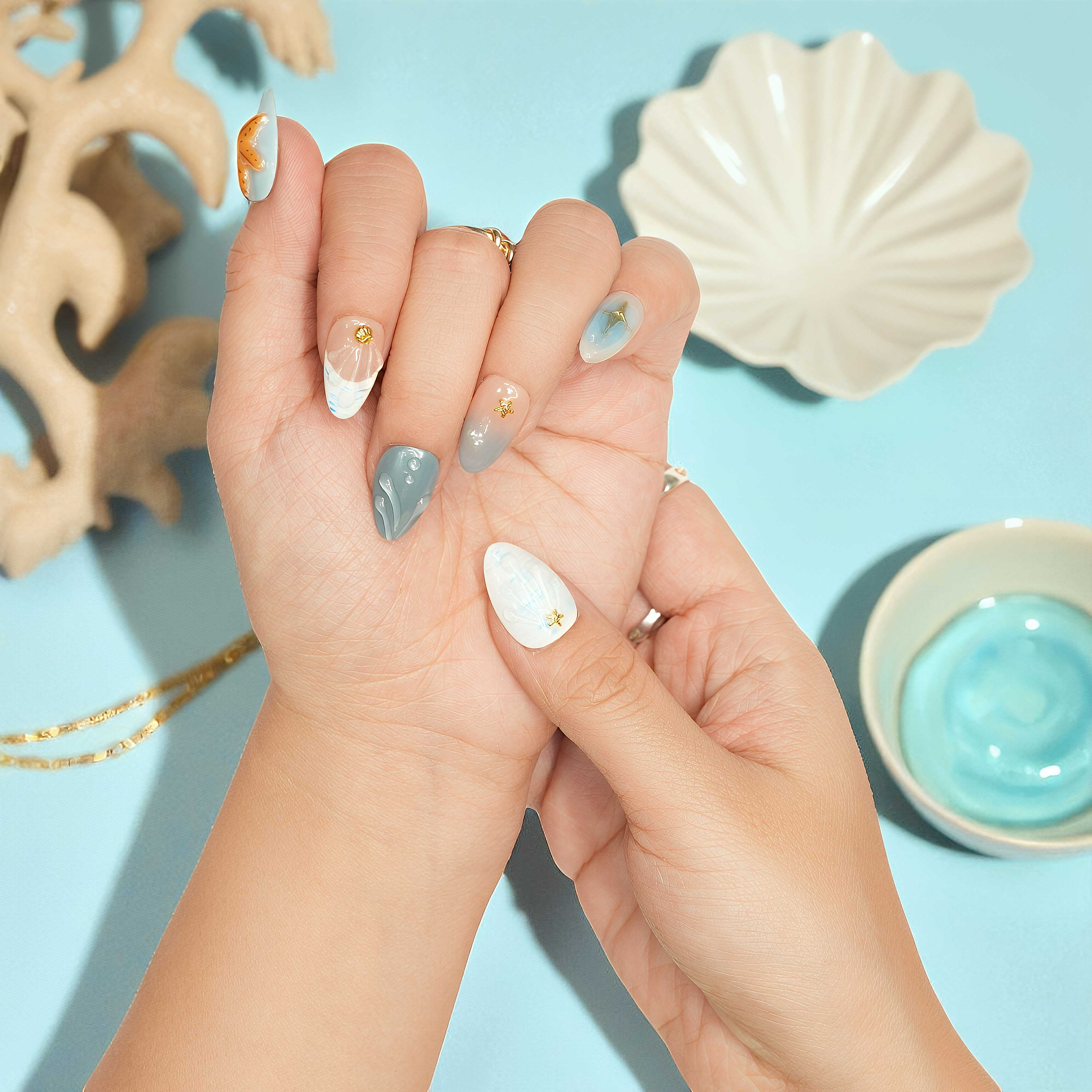 Bare minimum press on nails styled with peach, mint, and ocean blue tones – subtle sea-themed design.