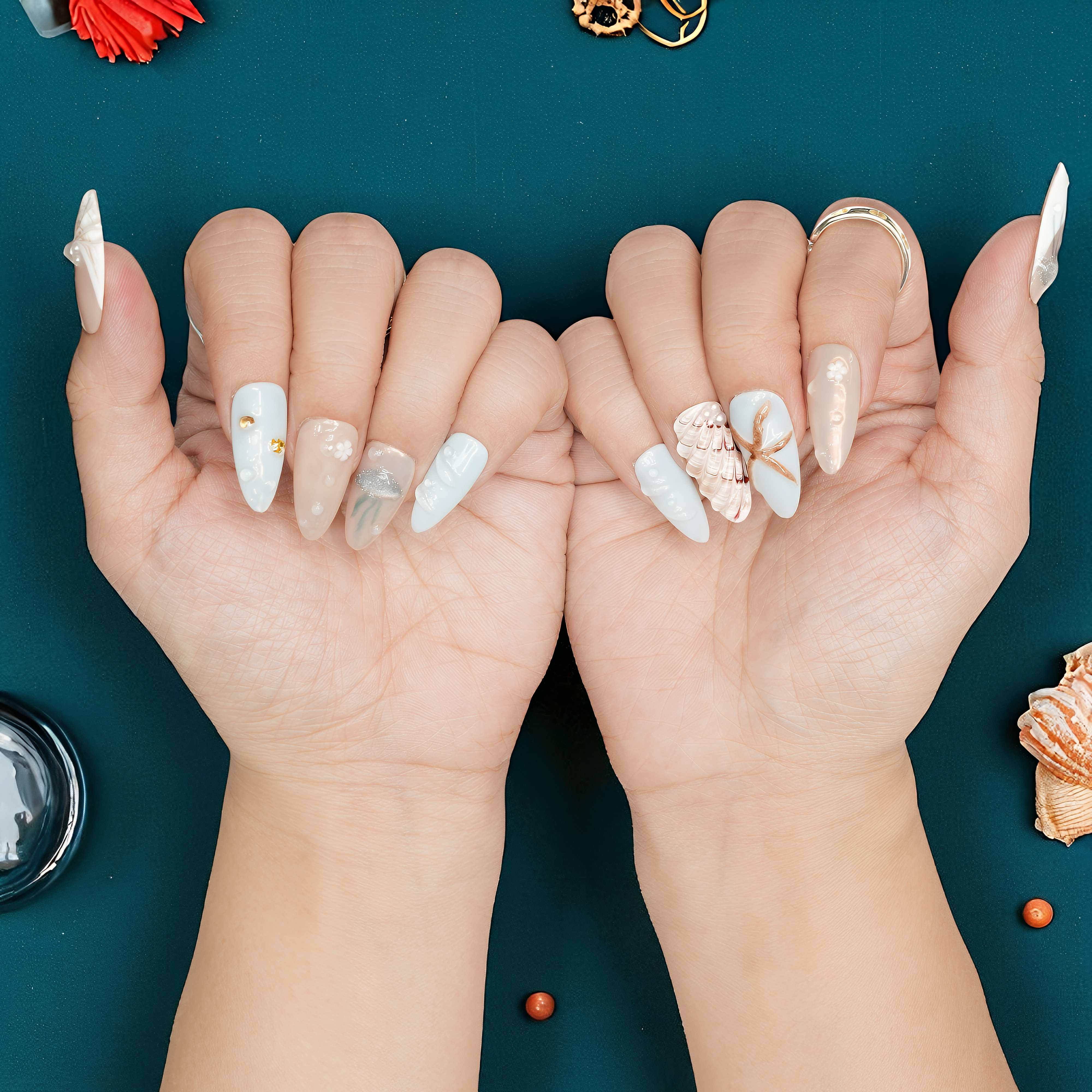 Jelly nails featuring golden seashell charm on nude and blue background