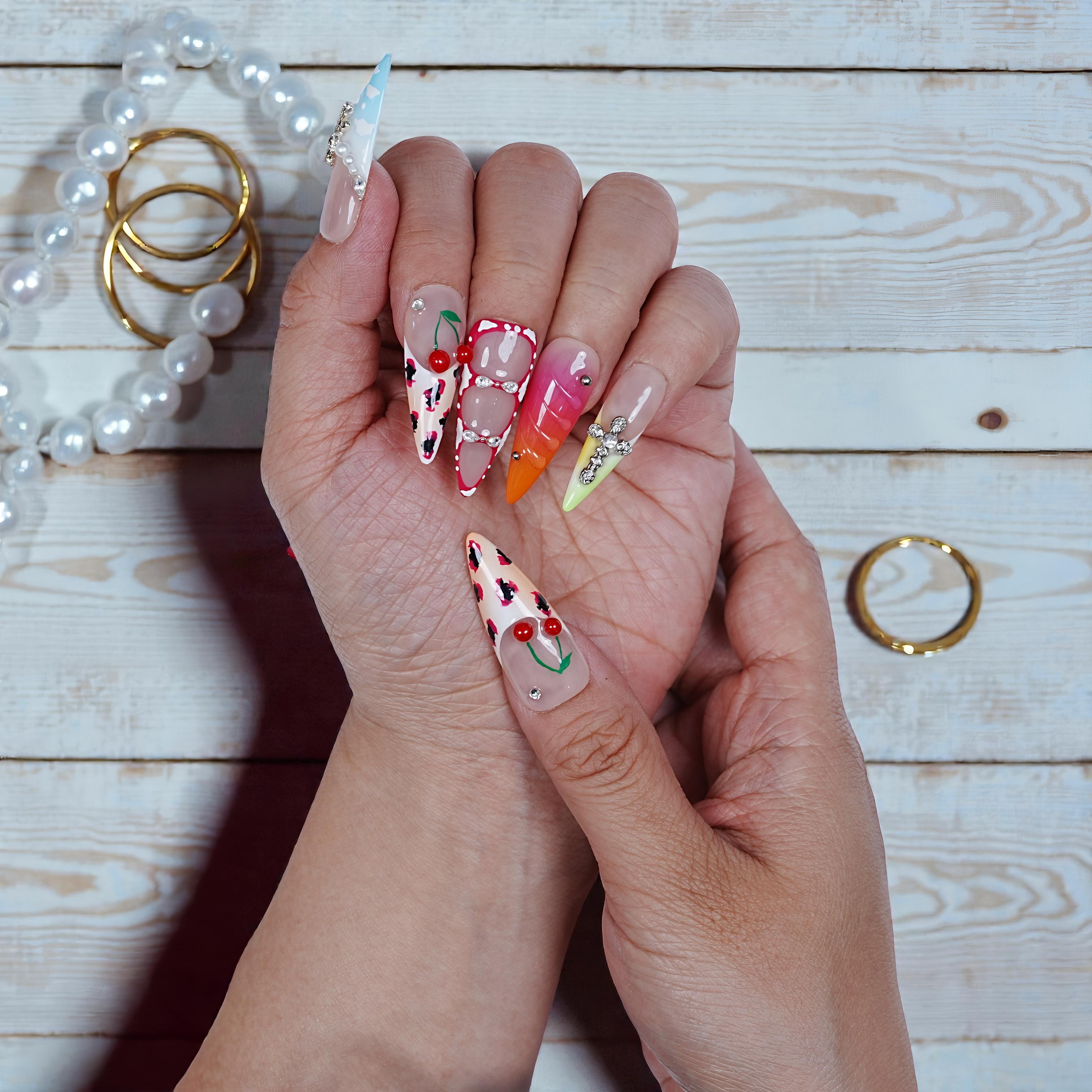 Hand with colorful nail art on a wooden surface with jewelry.