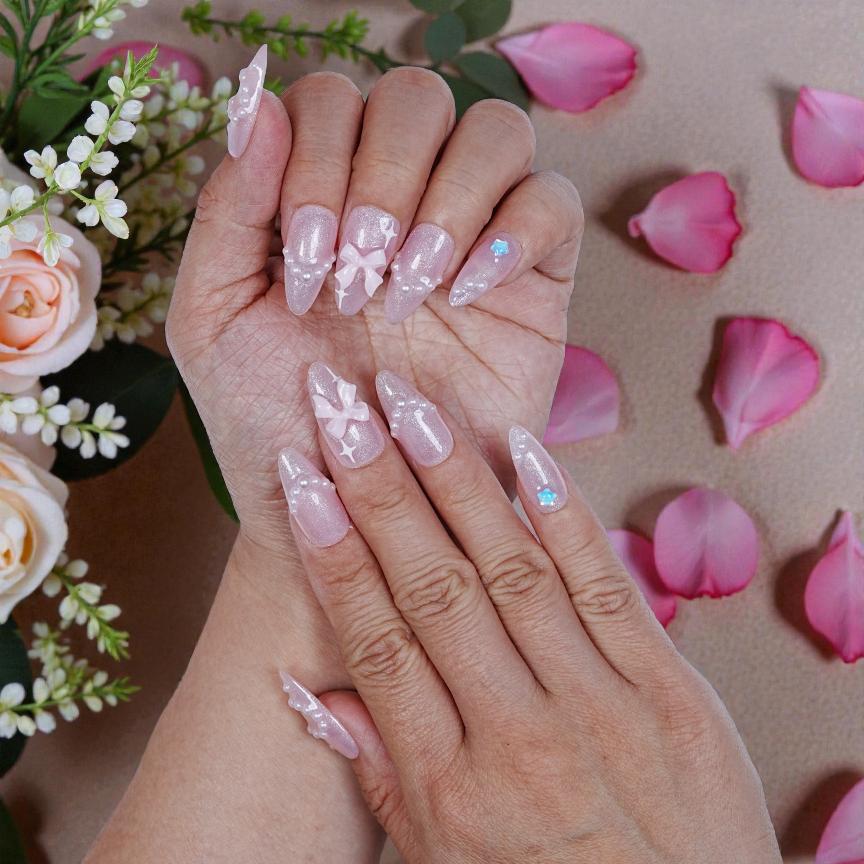 Model showing full set of pink artificial nails with pearl embellishments