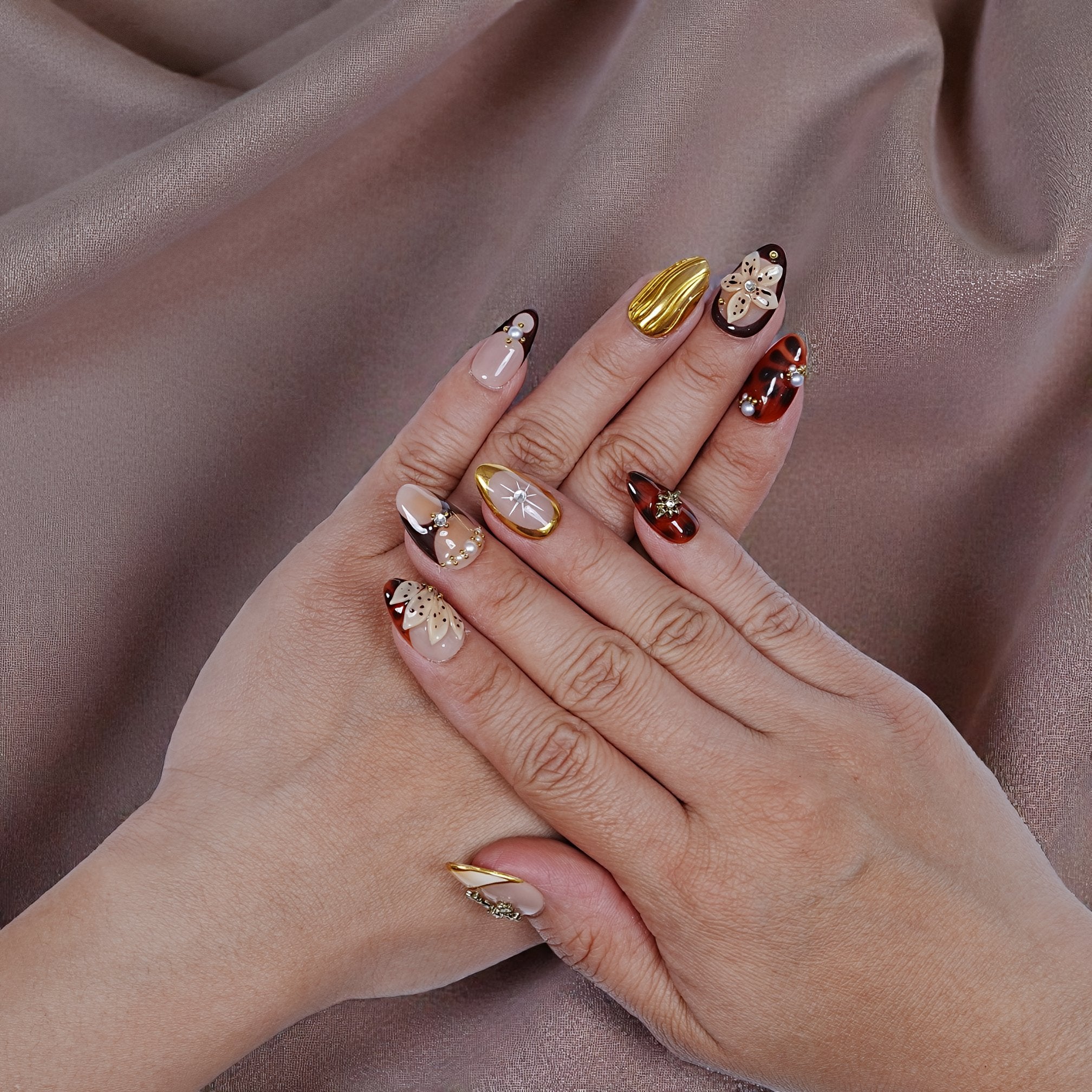 Luxury press on nails worn on hands showing almond shape and gold accents