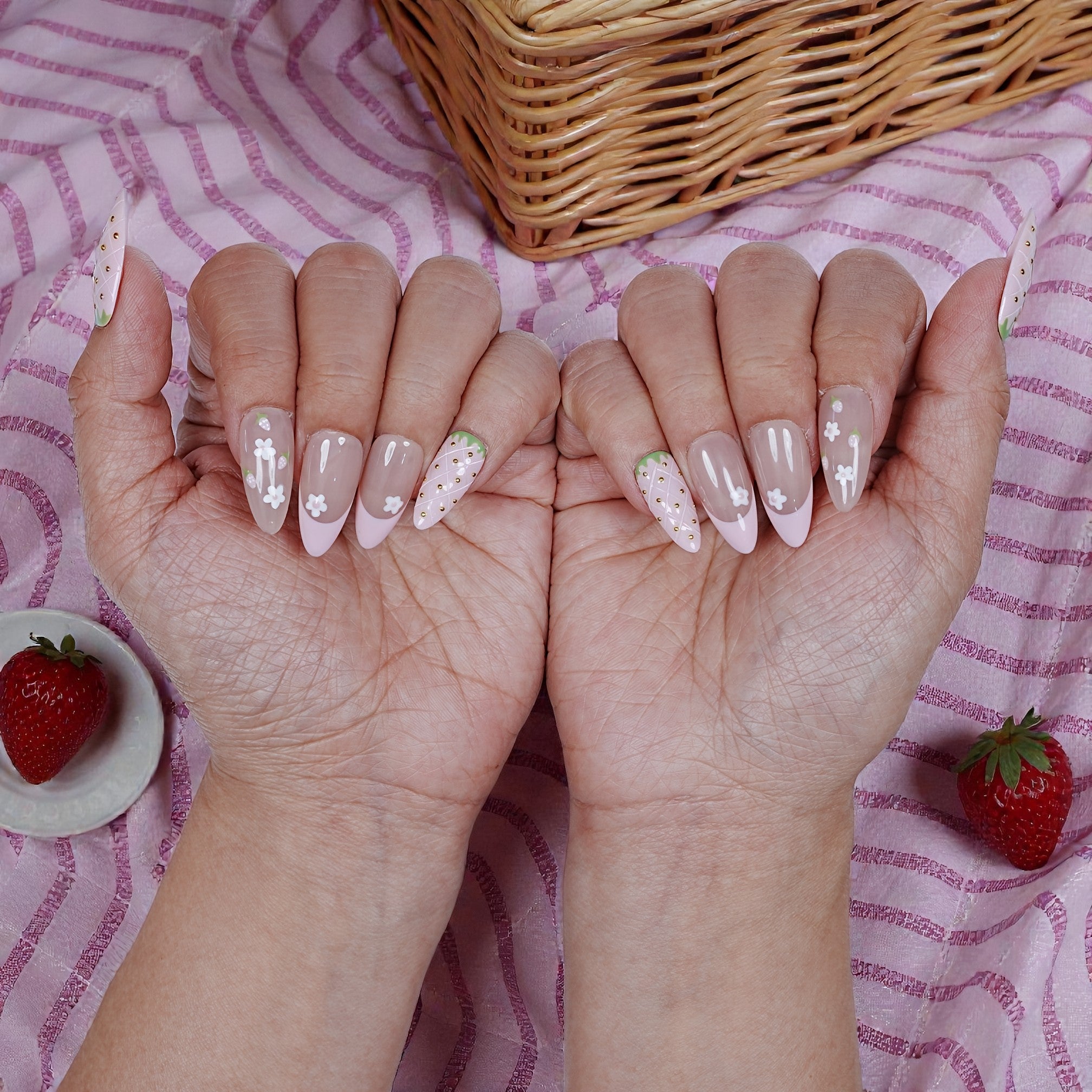 Handmade press on nails with strawberry and floral designs, pink striped fabric, strawberries
