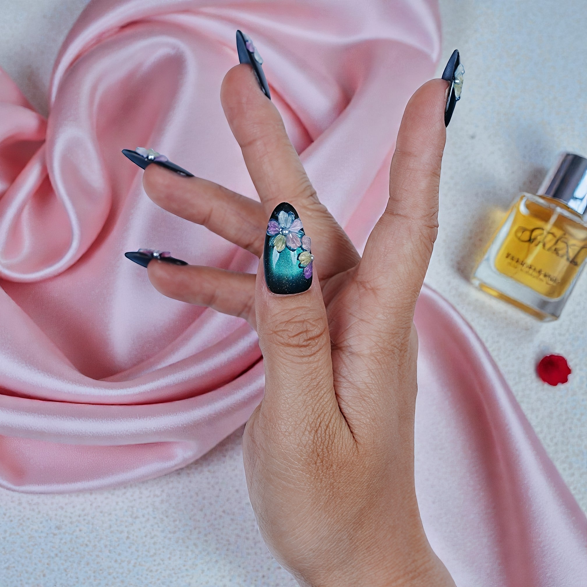 Hand with premium handmade press on nails, floral 3D nail art, pink silk and nail oil