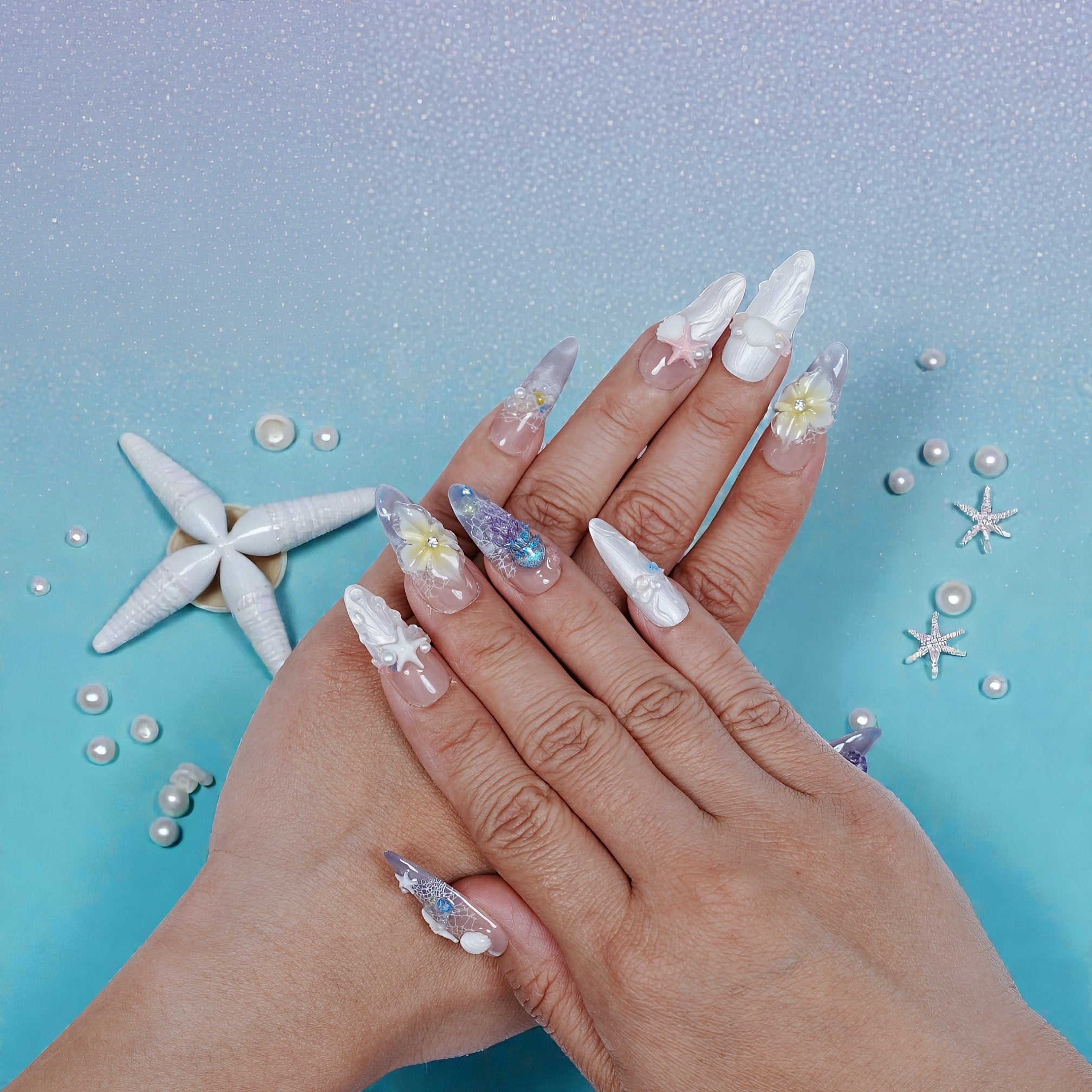 Hand displaying premium handmade press on nails with 3D seashell and pearl ocean designs