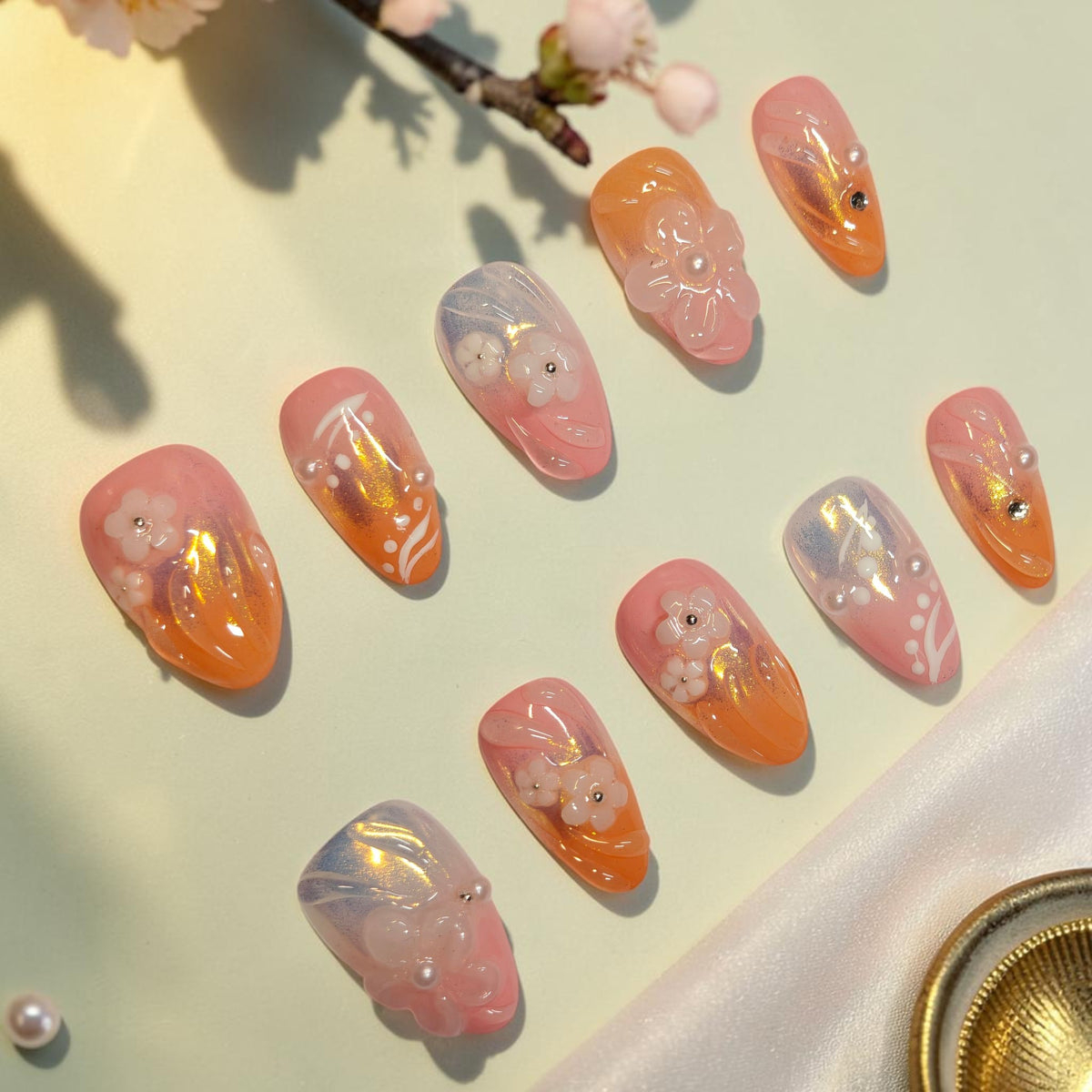 Coral Sunrise coral press on nails, short almond set blending pink and orange with golden aurora shimmer, 3D blossoms and pearls