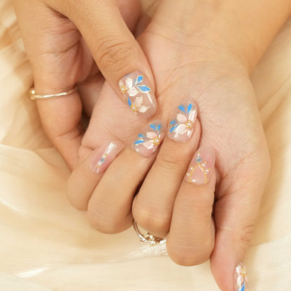 Glue on nails Australia featuring hand-painted floral designs in blue and white, perfect for spring and bridal looks.