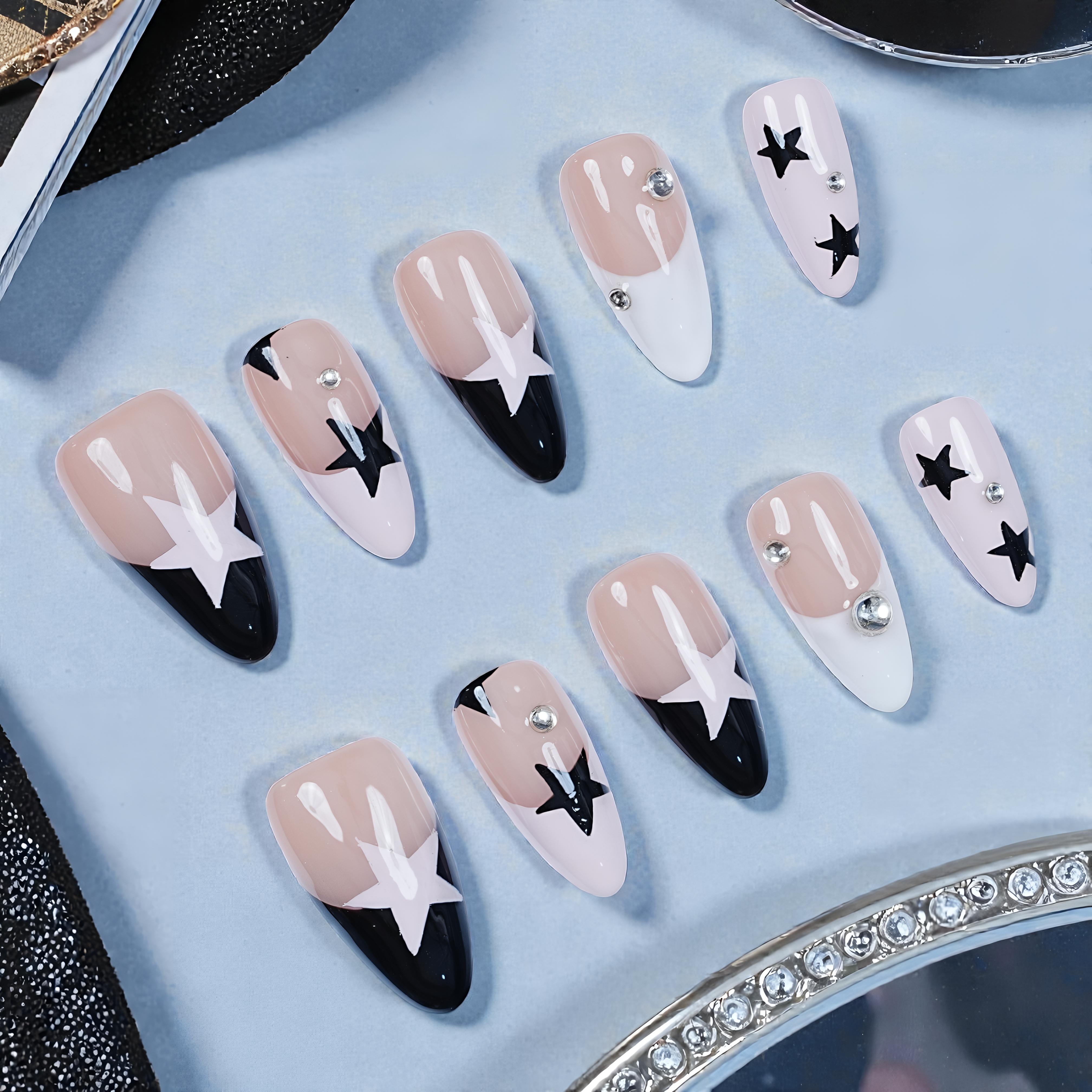 Handmade press on nails with black and white star designs and rhinestones on a light surface