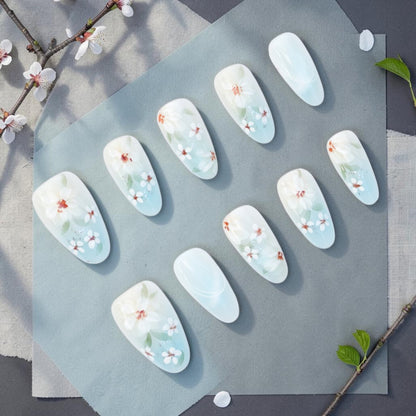 DSC00052 white floral press on nails full set with painted blossoms on a milky blue base laid flat