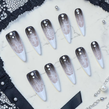 Handmade lace press on nails flat lay in smoky black and white with delicate lace, stiletto tips and crystals