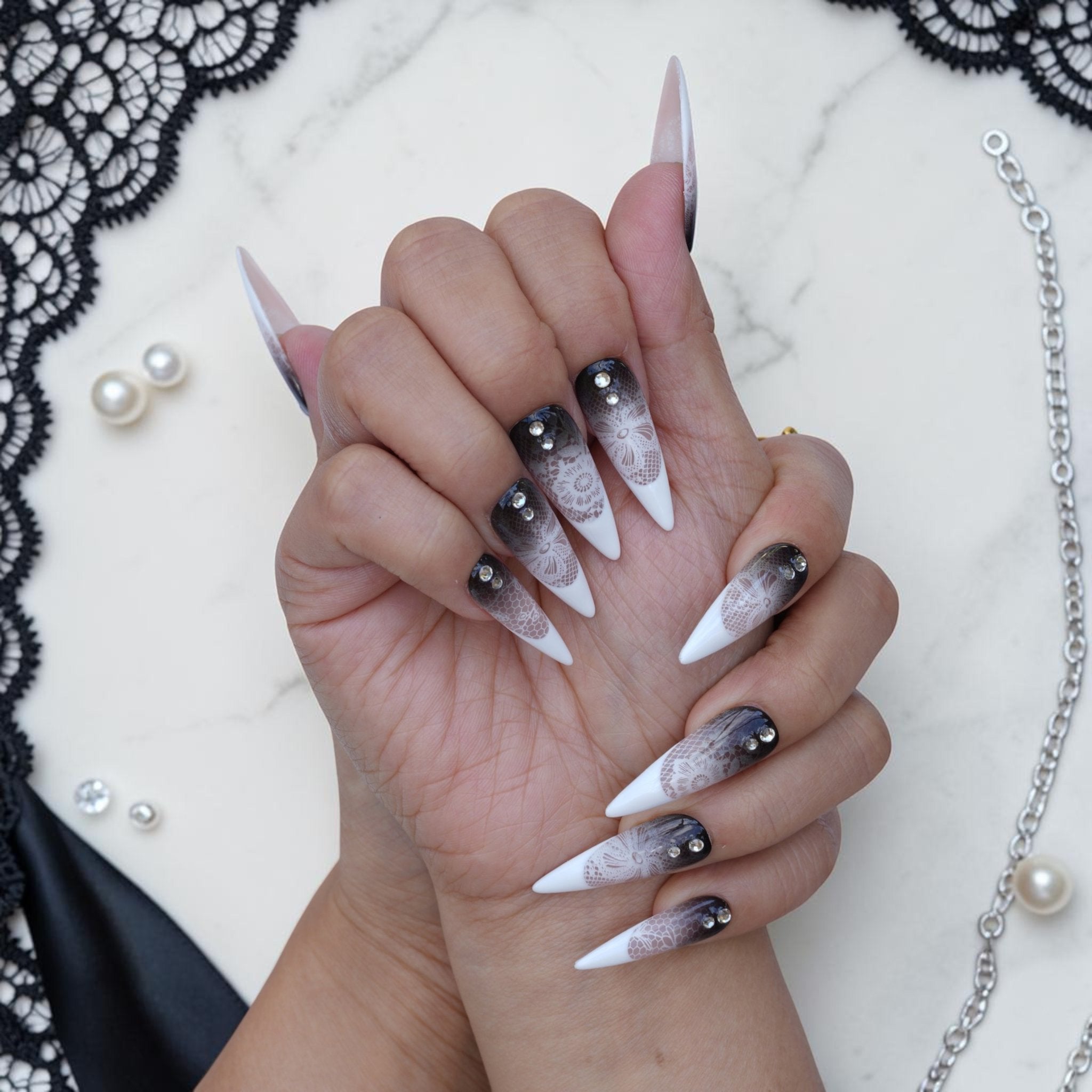 Lace press on nails shown on both hands in smoky black, white and nude